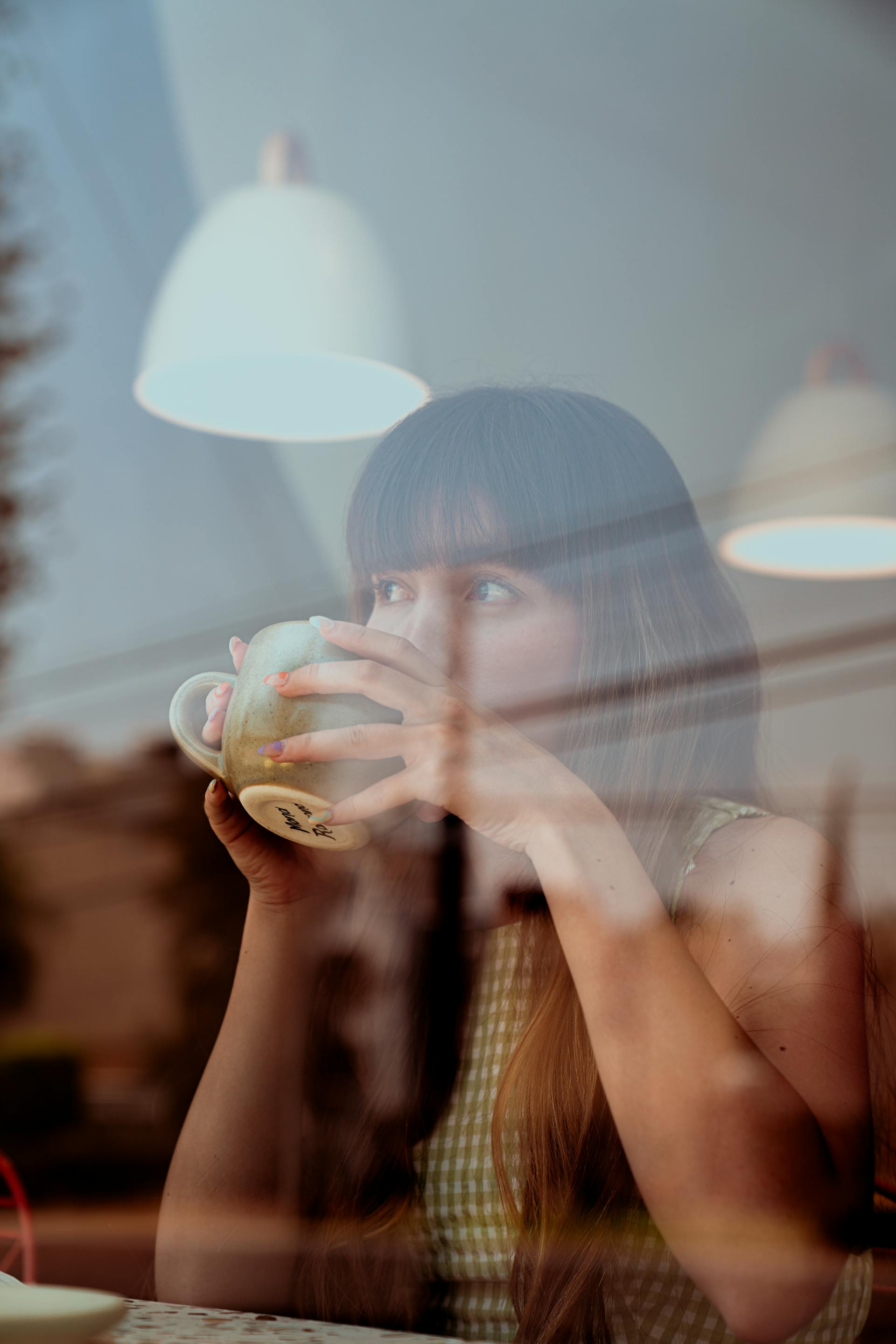 Eine Frau trinkt Kaffee und schaut aus dem Fenster des Cafés | Quelle: Pexels