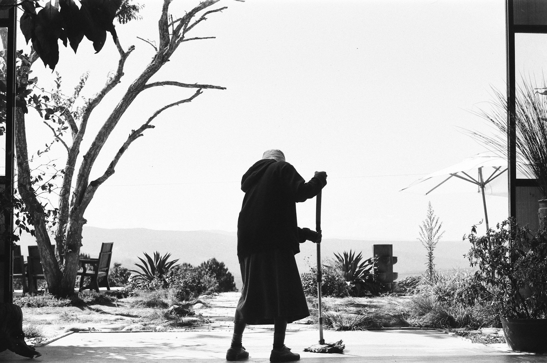 Graustufenaufnahme einer älteren Frau, die den Boden putzt | Quelle: Unsplash