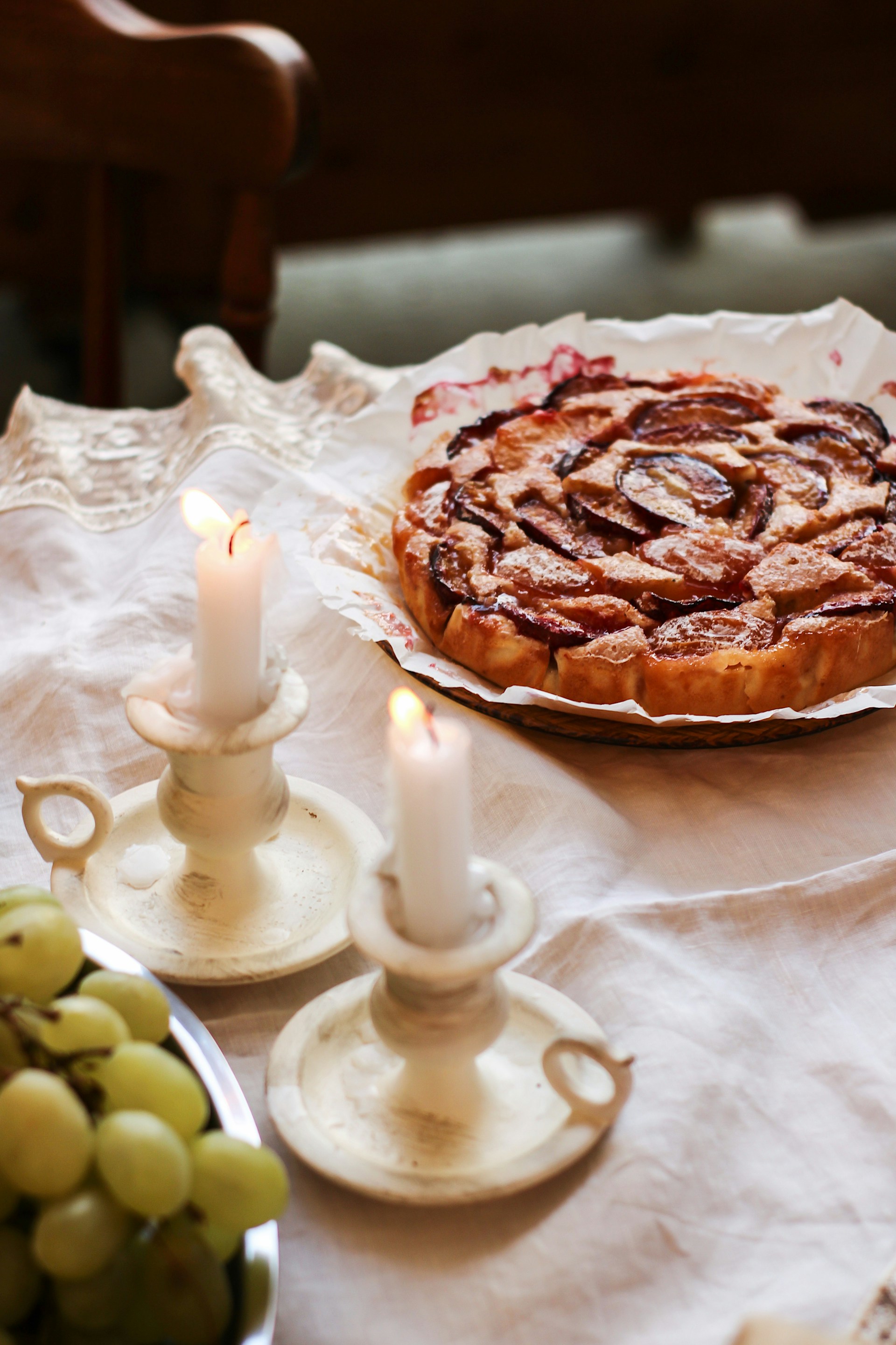 Eine Schale mit Weintrauben, Kerzen und ein Teller mit Kuchen auf dem Tisch | Quelle: Unsplash