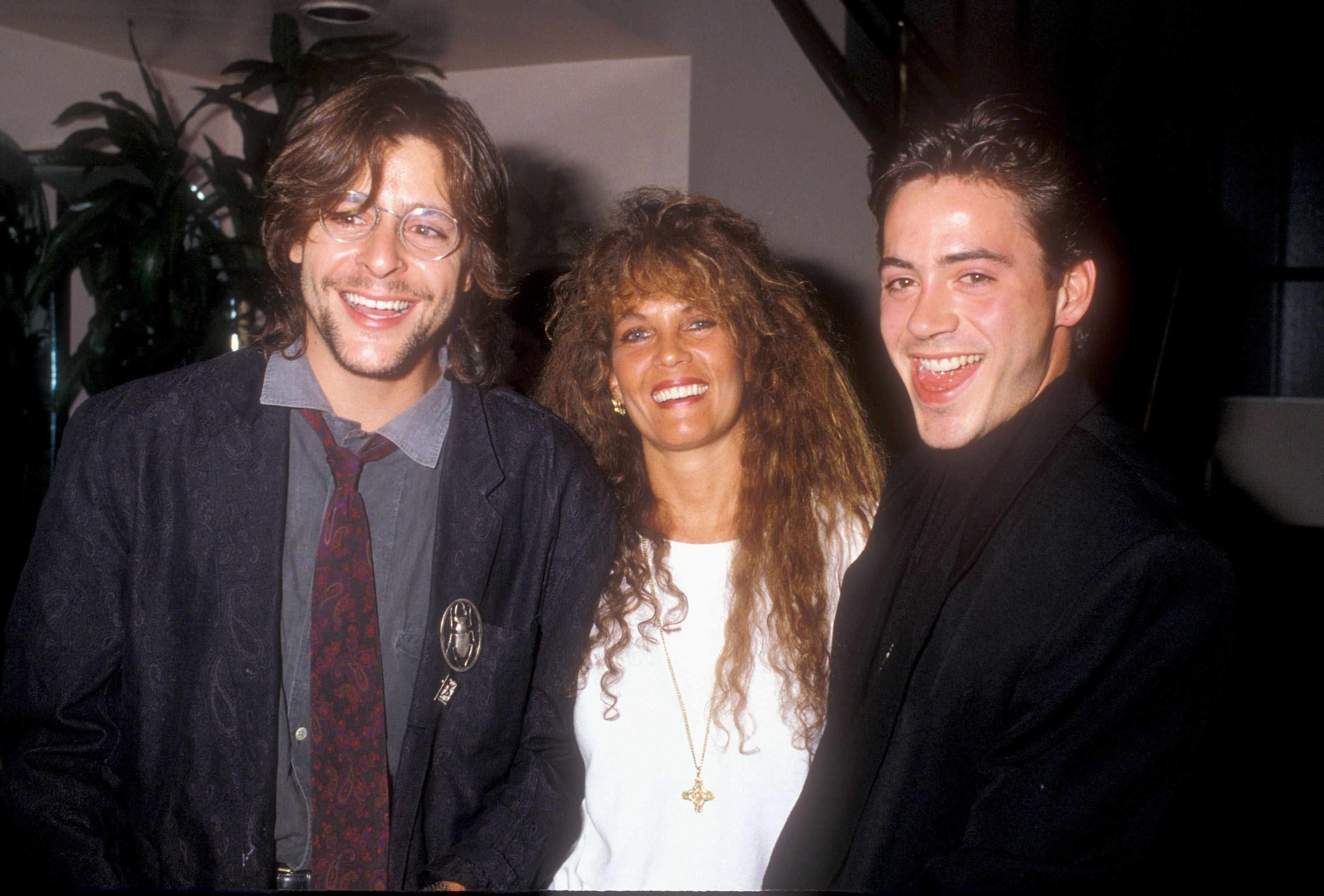 Mit einem strahlenden Lächeln an der Seite der Schmuckdesignerin Loree Rodkin und eines ausgelassenen Robert Downey Jr. nahm der Schauspieler 1988 an einer Benefizveranstaltung von Amnesty International teil. | Quelle: Getty Images
