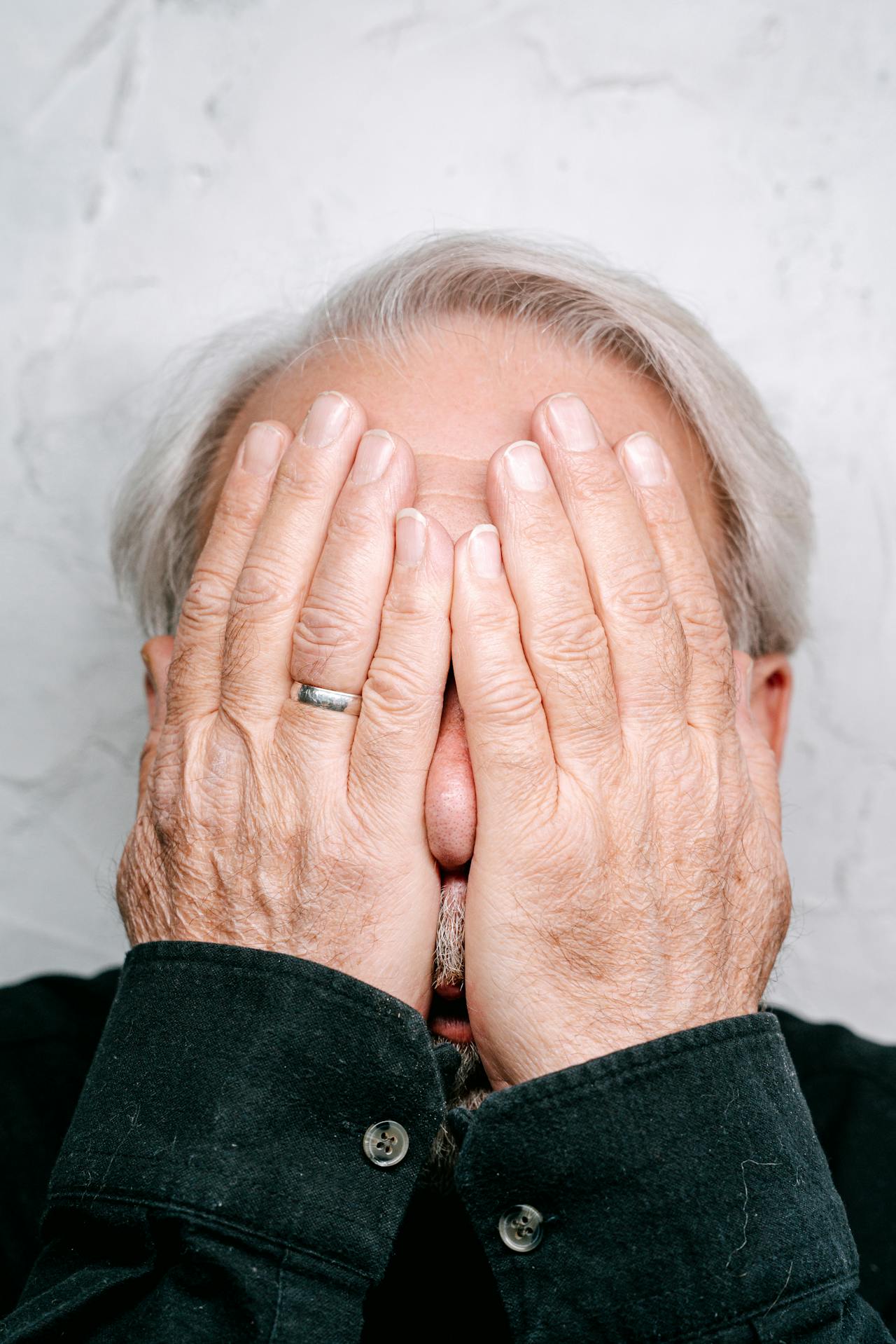 Ein verzweifelter älterer Mann, der sein Gesicht bedeckt | Quelle: Pexels
