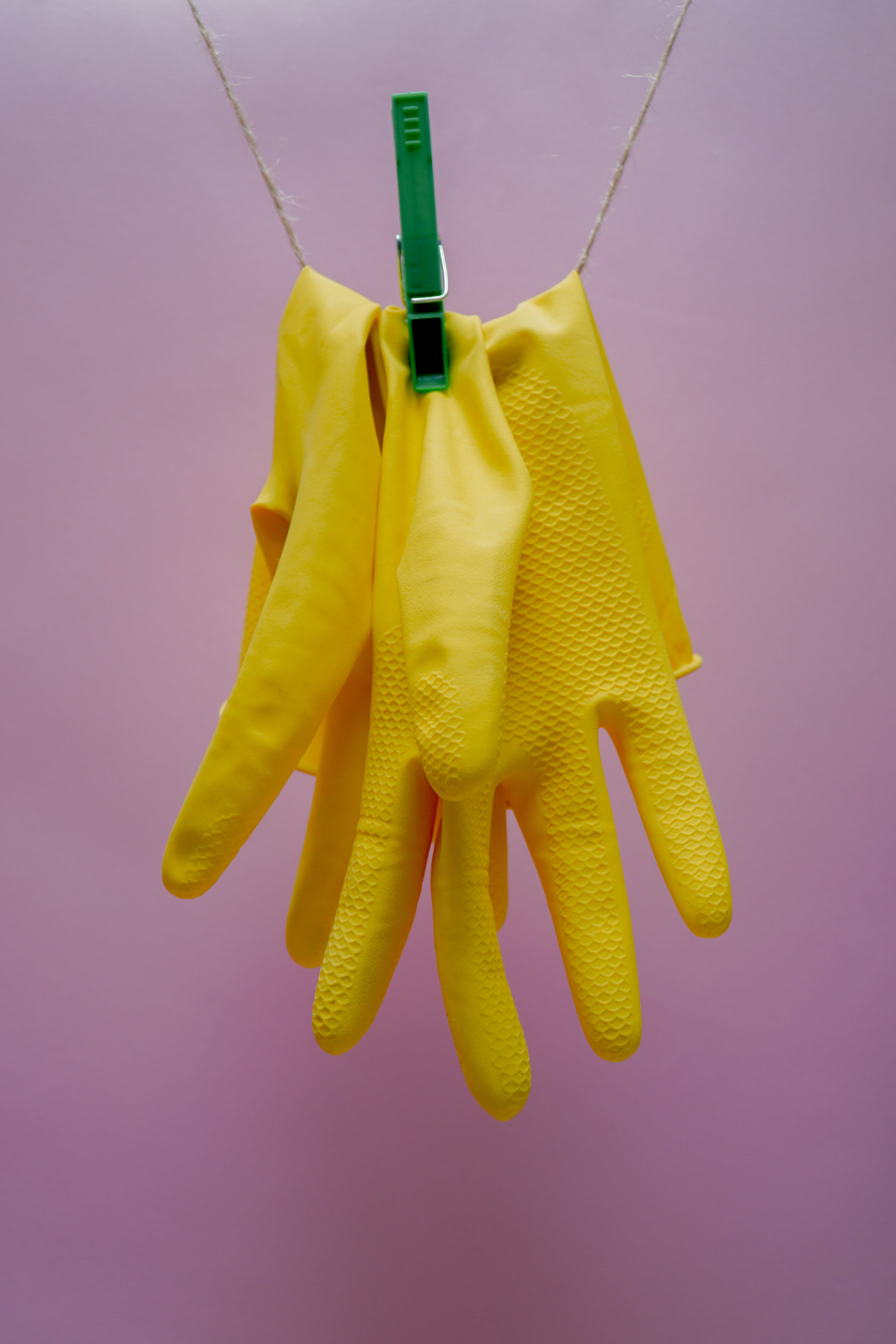 Gelbe Handschuhe, die an einer Wäscheklammer hängen | Quelle: Unsplash