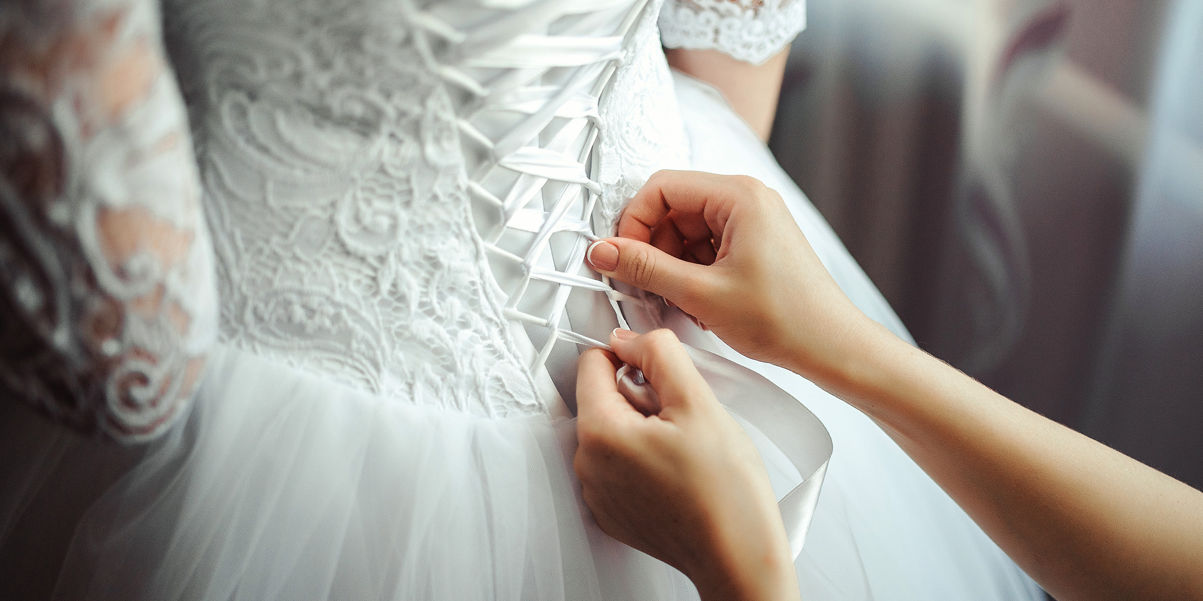 Eine Frau schnürt das Mieder eines Hochzeitskleides | Quelle: Freepik
