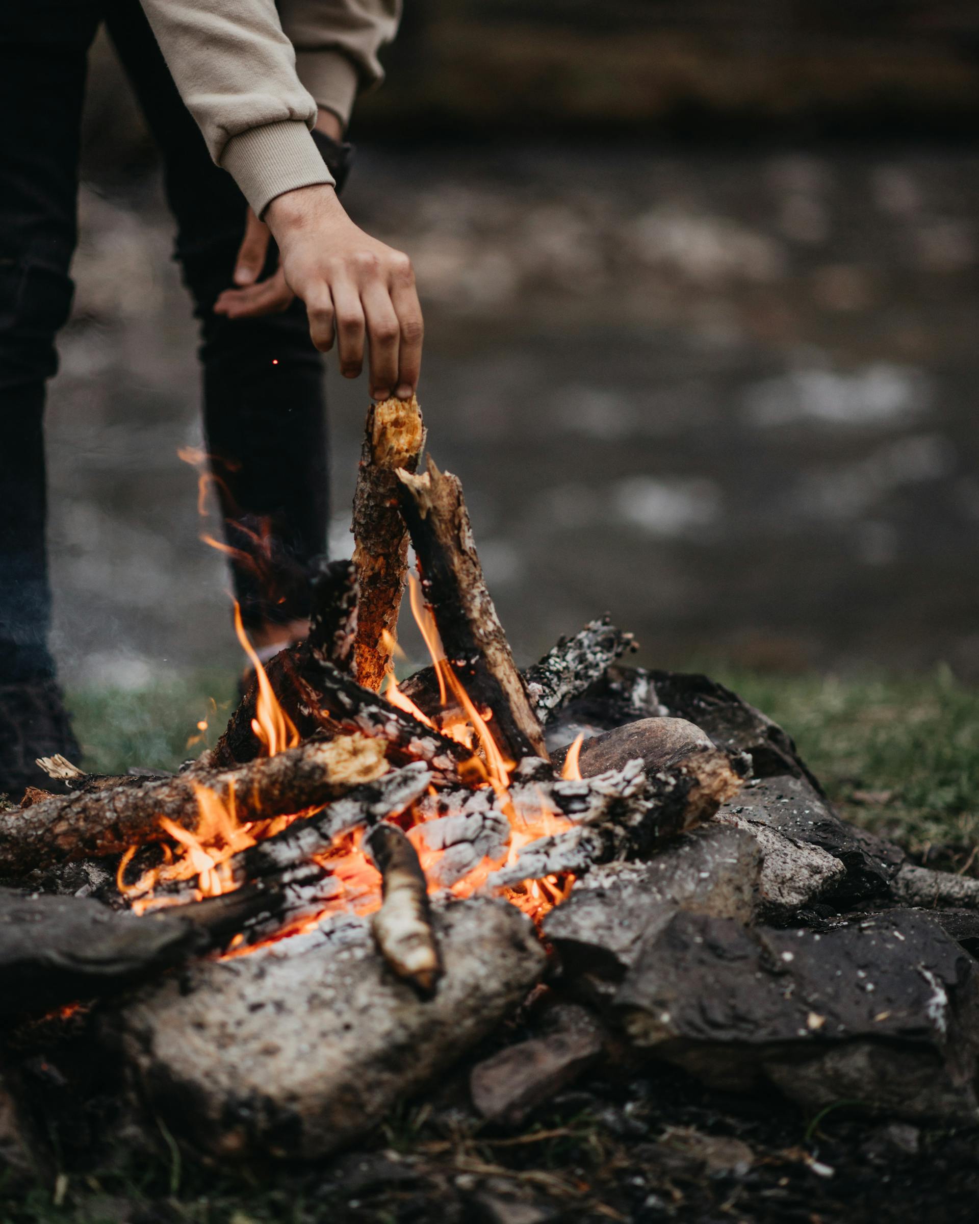 Ein Mann, der Holz in ein Feuer legt | Quelle: Pexels
