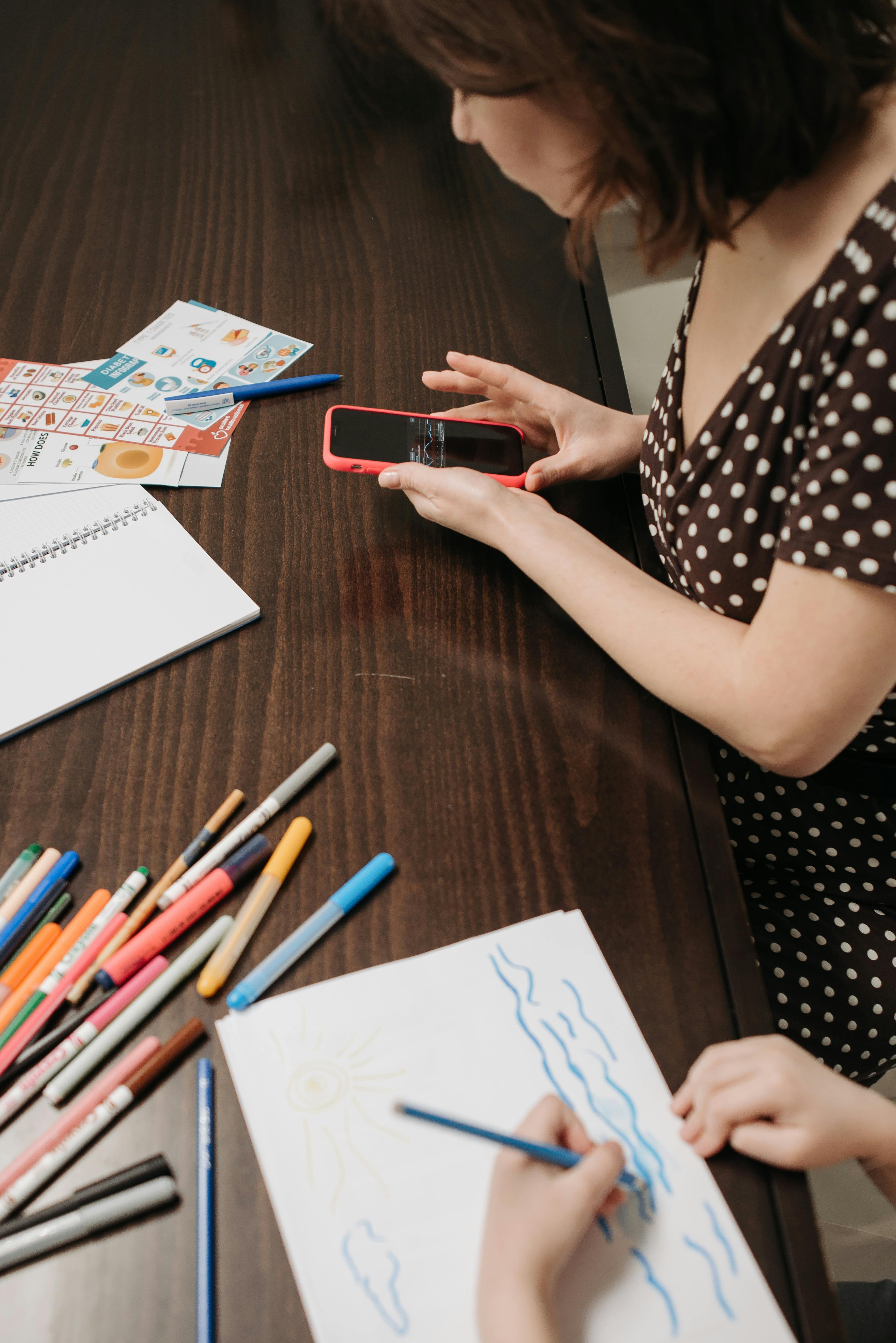 Ein Kind, das neben seinem Elternteil zeichnet | Quelle: Pexels