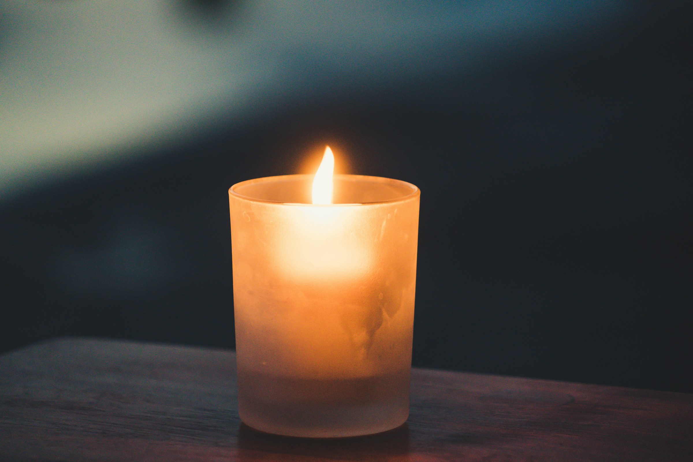 Eine brennende Kerze auf einer Holzoberfläche | Quelle: Unsplash