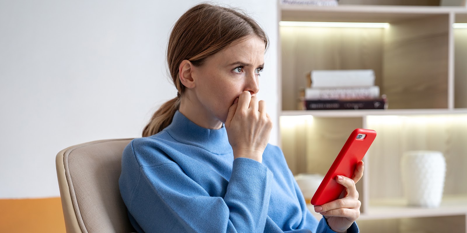 Eine nachdenkliche Frau sitzt mit einem Telefon in der Hand | Quelle: Shutterstock