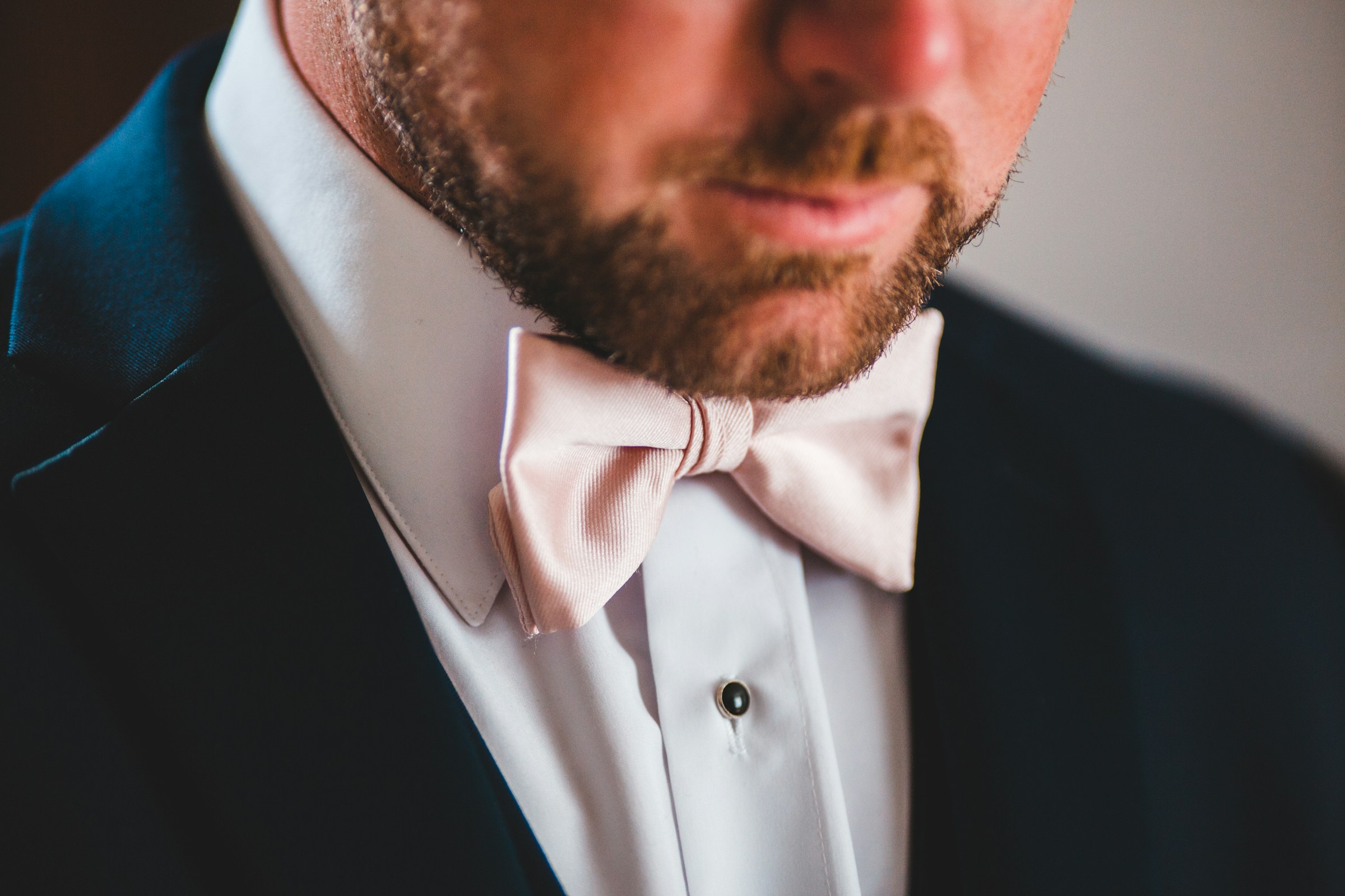 Ein Mann im Smoking mit einer rosa Fliege | Quelle: Unsplash