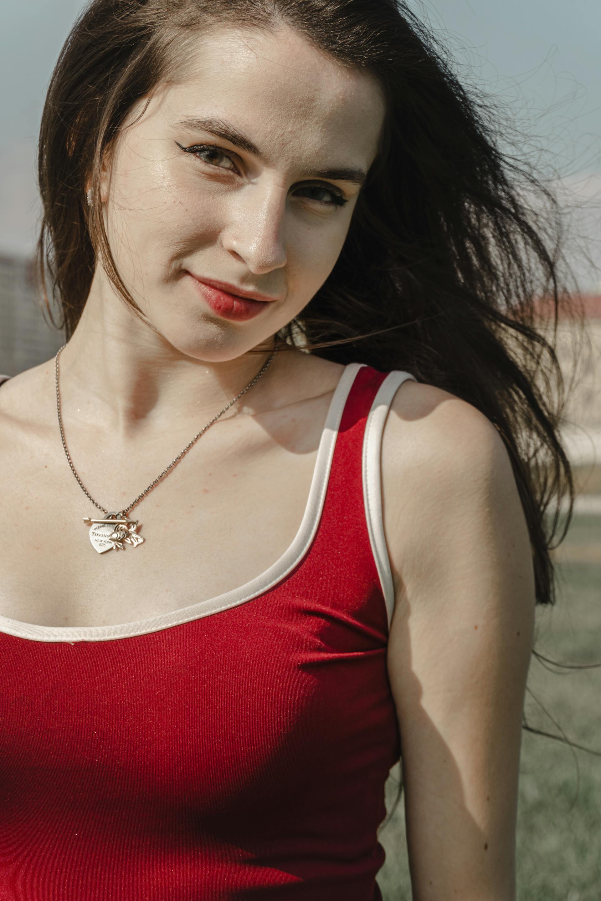 Eine Frau in einem roten Top, die lächelnd im Freien steht | Quelle: Pexels