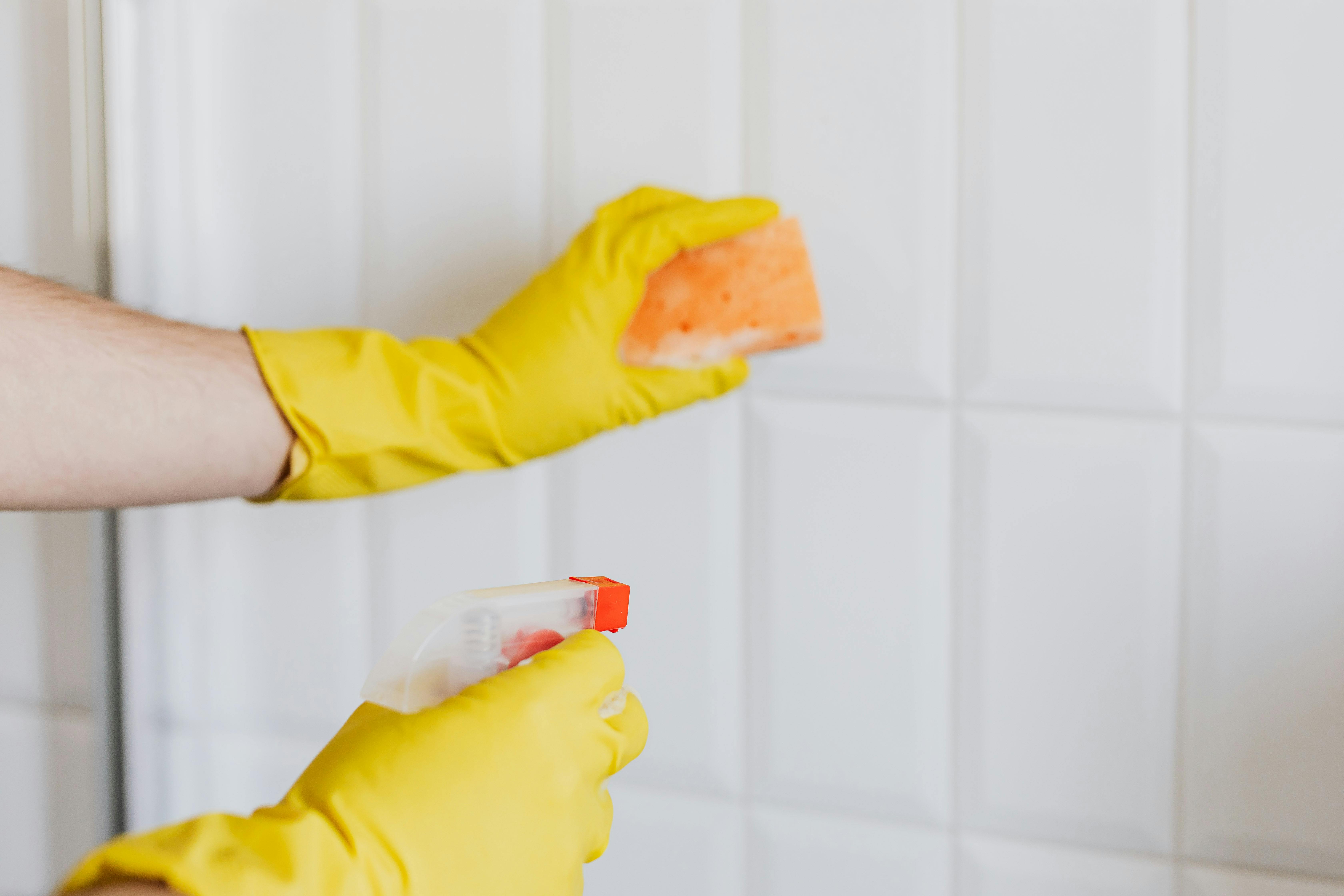 Eine Person, die ein Badezimmer mit gelben Handschuhen putzt | Quelle: Pexels