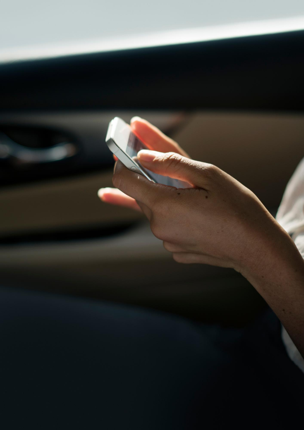Eine Frau hält ihr Handy in der Hand, während sie in einem Auto sitzt | Quelle: Freepik