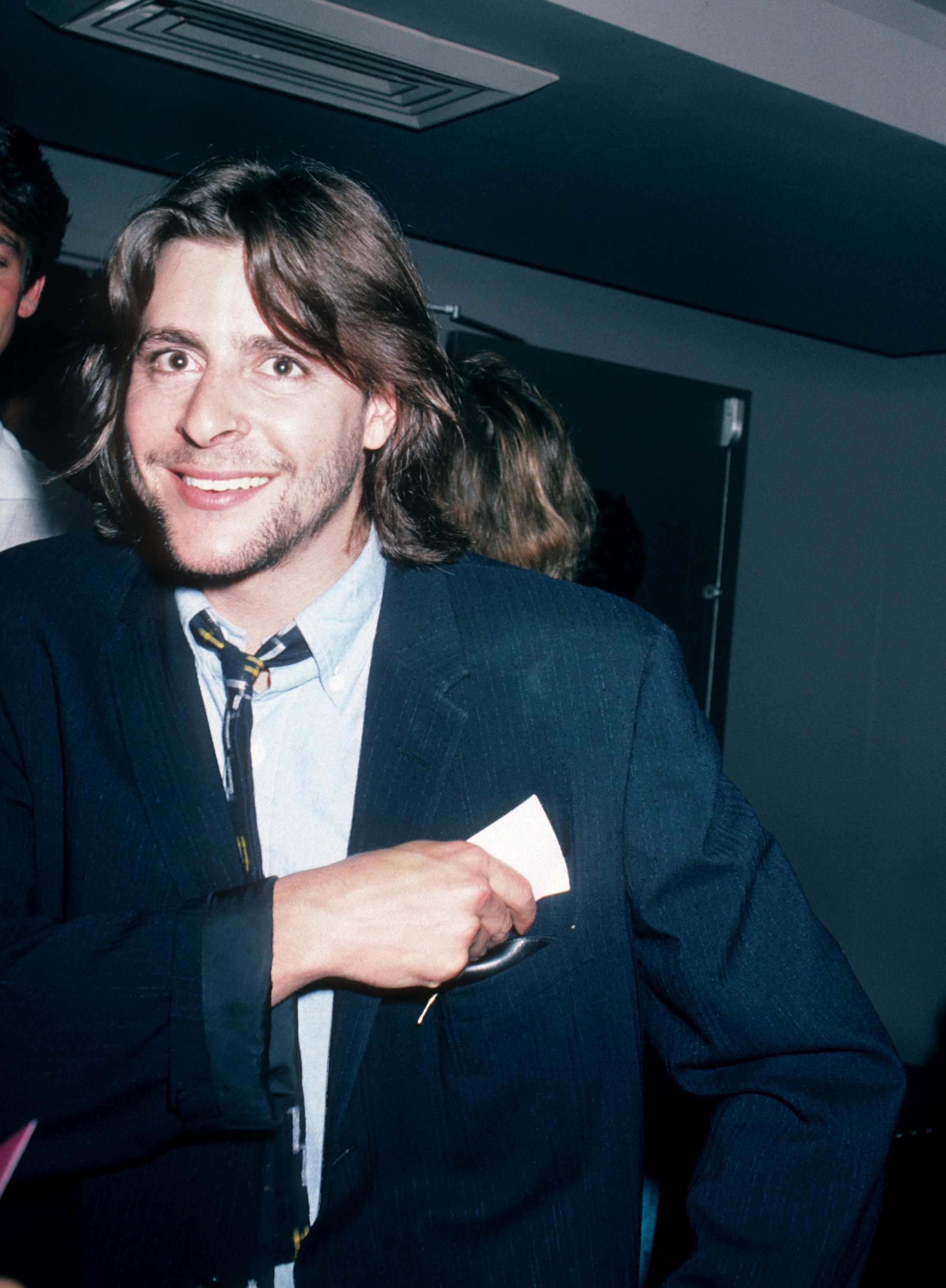 Mit einem herzlichen Lächeln im Gesicht steckte der junge Schauspieler eine Karte in seine Jackentasche und genoss 1986 einen Abend bei der Peter-Max-Kunstausstellung im „Marylou’s“ in New York City. | Quelle: Getty Images