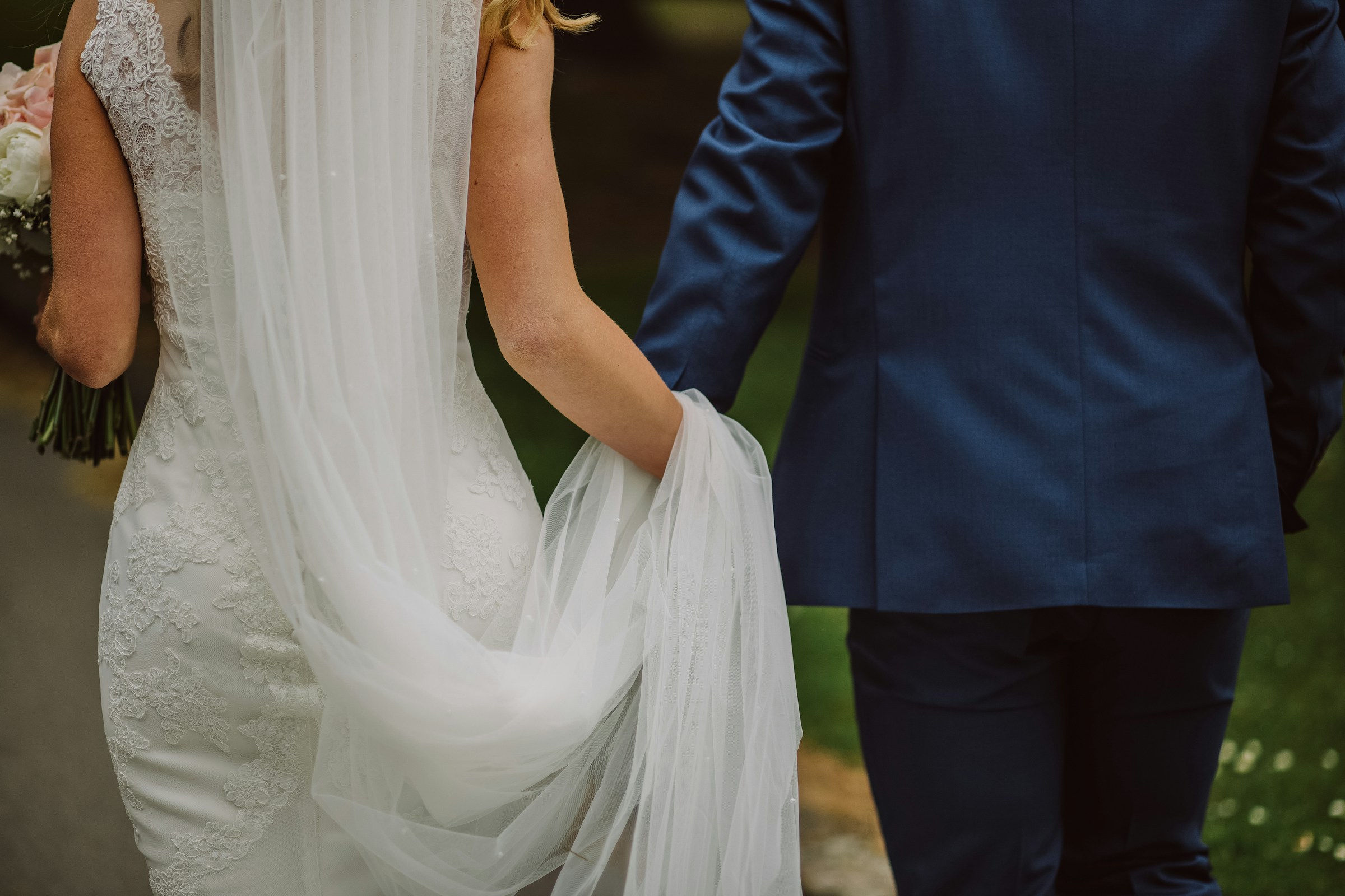 Eine Braut und ein Bräutigam, die sich beim Gehen an den Händen halten | Quelle: Unsplash