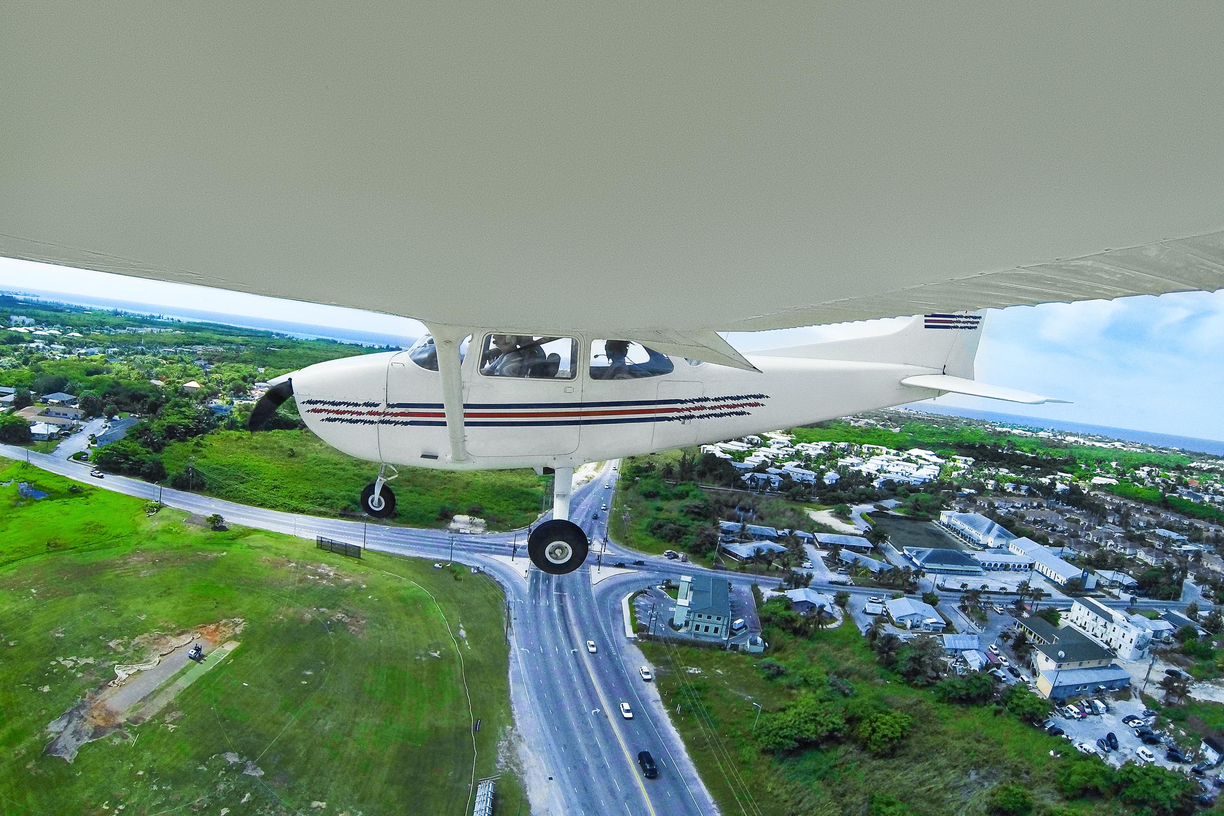 Fernkameraaufnahme eines fliegenden Cesna-Flugzeugs und Menschen in der Kabine auf einer touristischen Reise. | Quelle: Getty Images