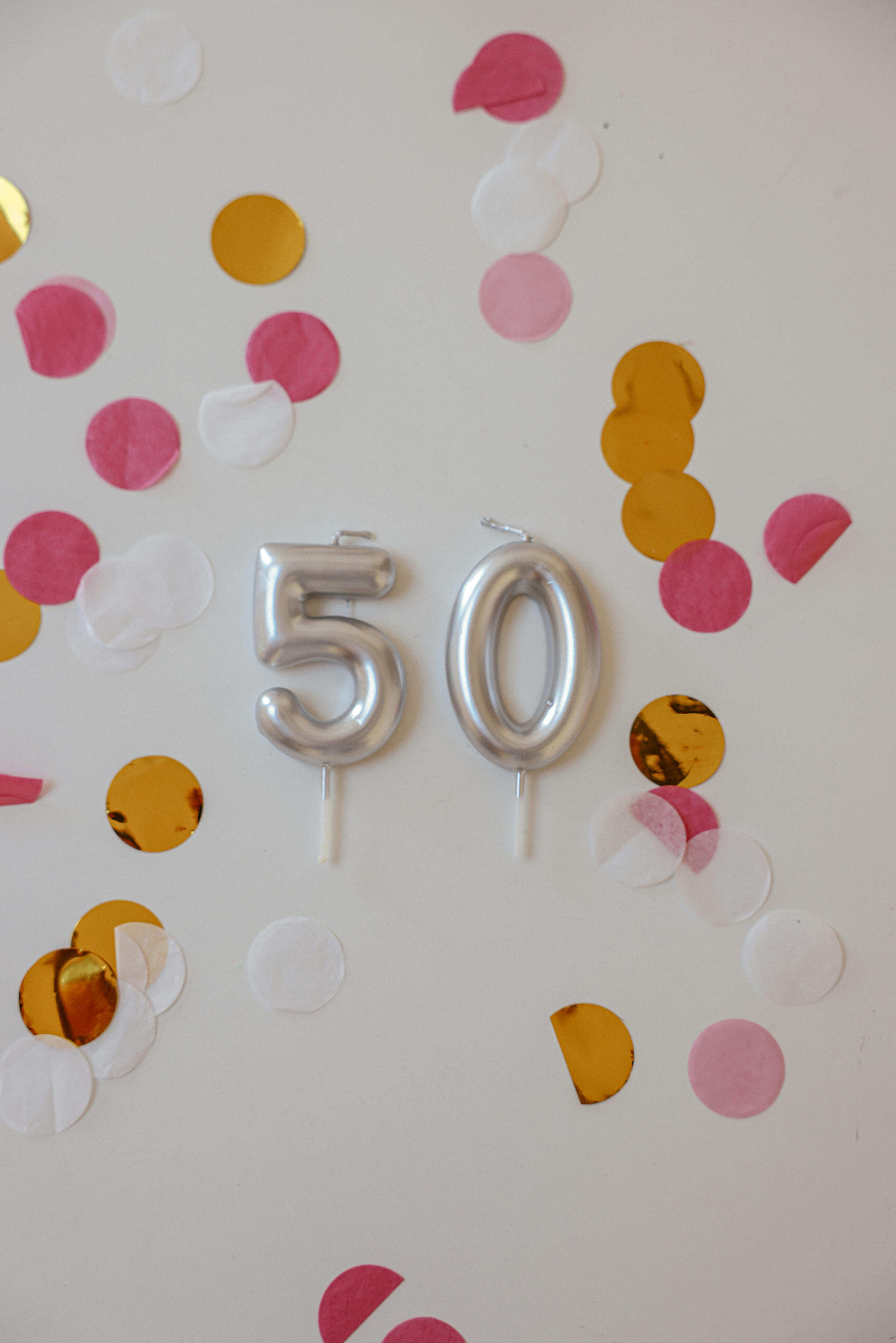 Silberne Luftballons und buntes Konfetti an einer Wand | Quelle: Pexels