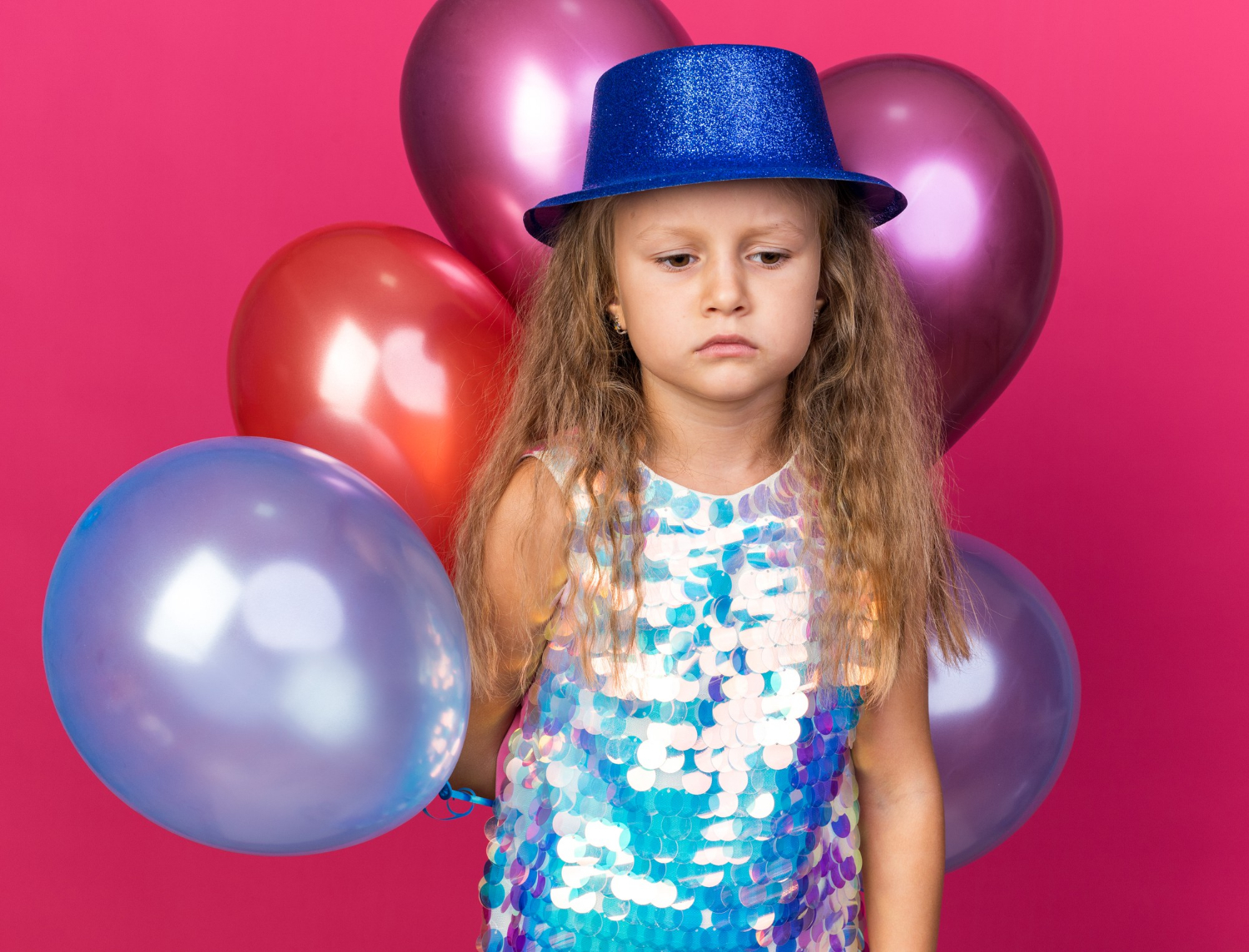 Ein trauriges kleines Mädchen, das bunte Luftballons hält | Quelle: Freepik