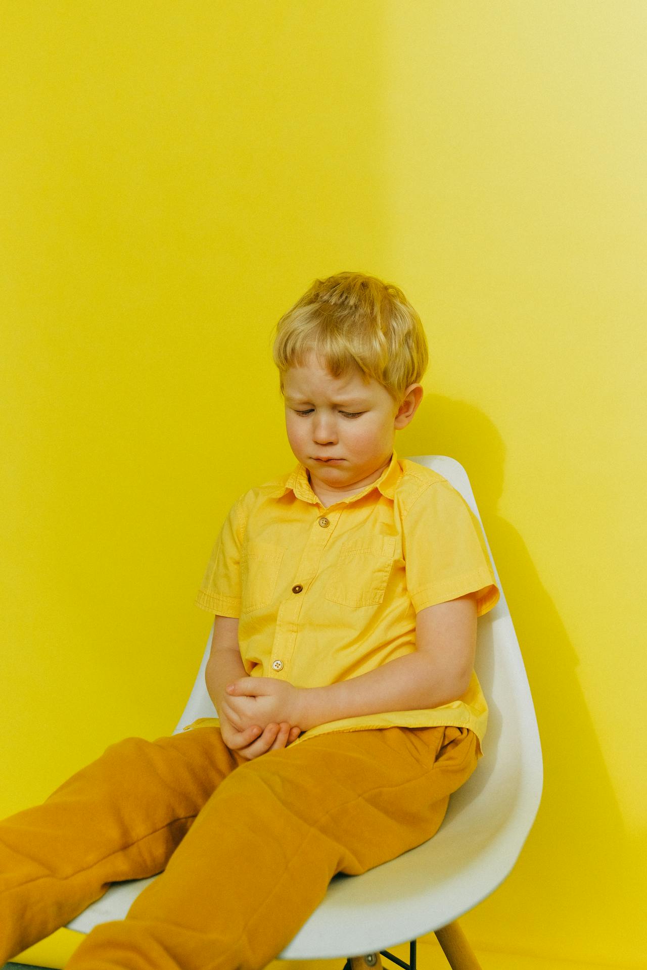 Ein trauriger kleiner Junge, der auf einem Stuhl sitzt | Quelle: Pexels