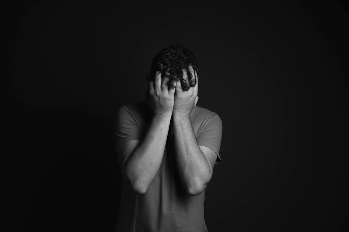 Ein trauriger Mann, der sein Gesicht bedeckt | Quelle: Pexels