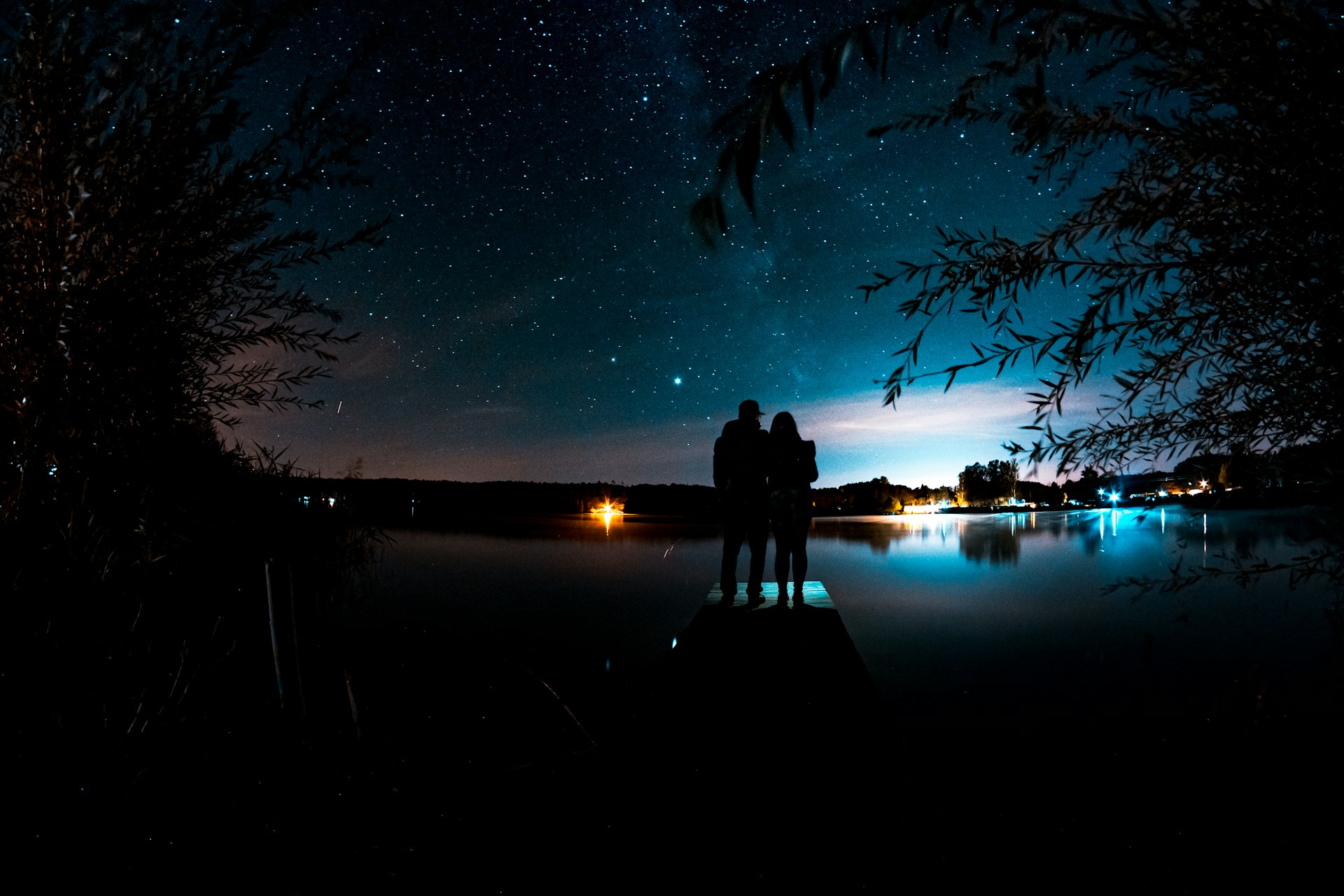 Ein junges Paar bewundert an einem malerischen Abend die Sterne von einem Pier aus | Quelle: Unsplash