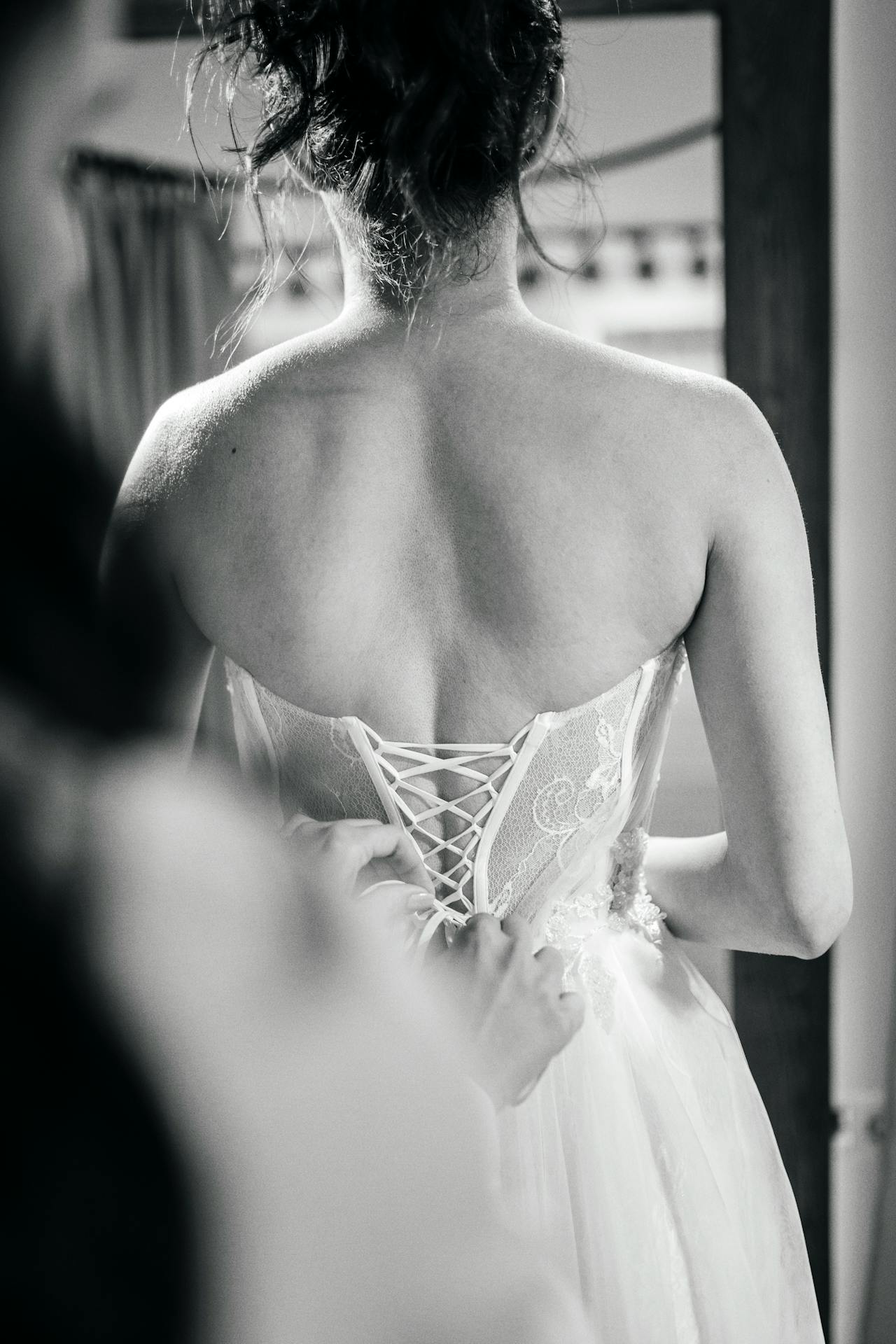 Eine Frau hilft einer Braut mit ihrem Kleid | Quelle: Pexels