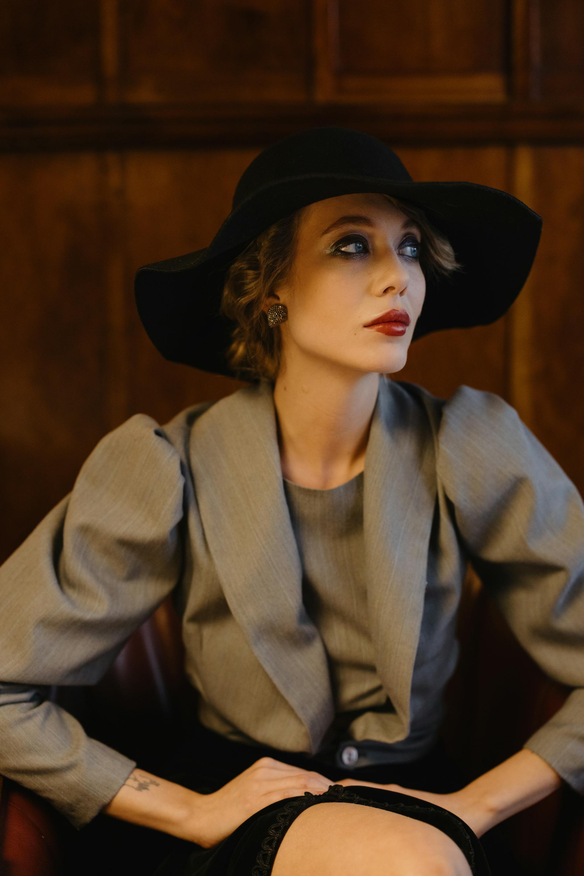 Eine modische Frau mit rotem Lippenstift und einem schwarzen Hut, die zur Seite schaut | Quelle: Pexels