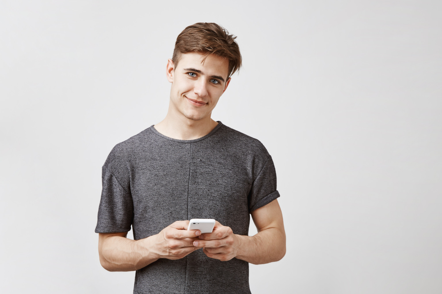 Ein lächelnder junger Mann, der sein Telefon hält | Quelle: Freepik