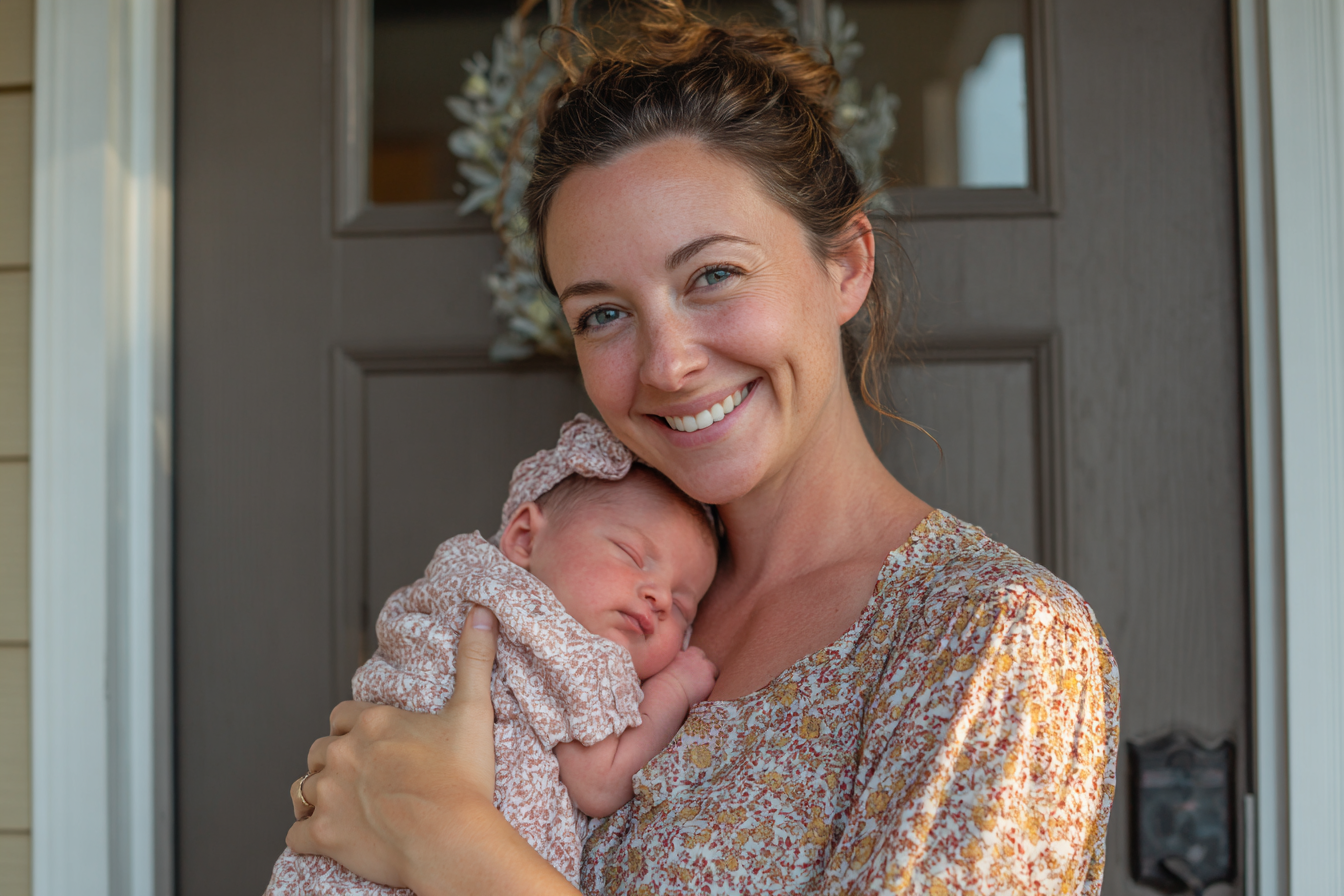 Eine lächelnde Frau hält ihr neugeborenes Mädchen im Arm | Quelle: Midjourney