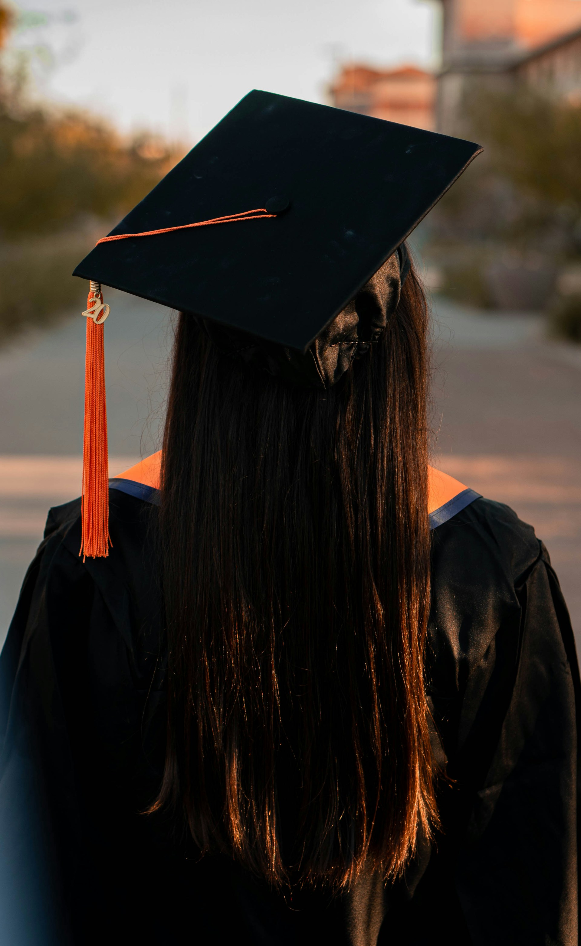 Eine junge Absolventin steht vor ihrem Campus | Quelle: Unsplash