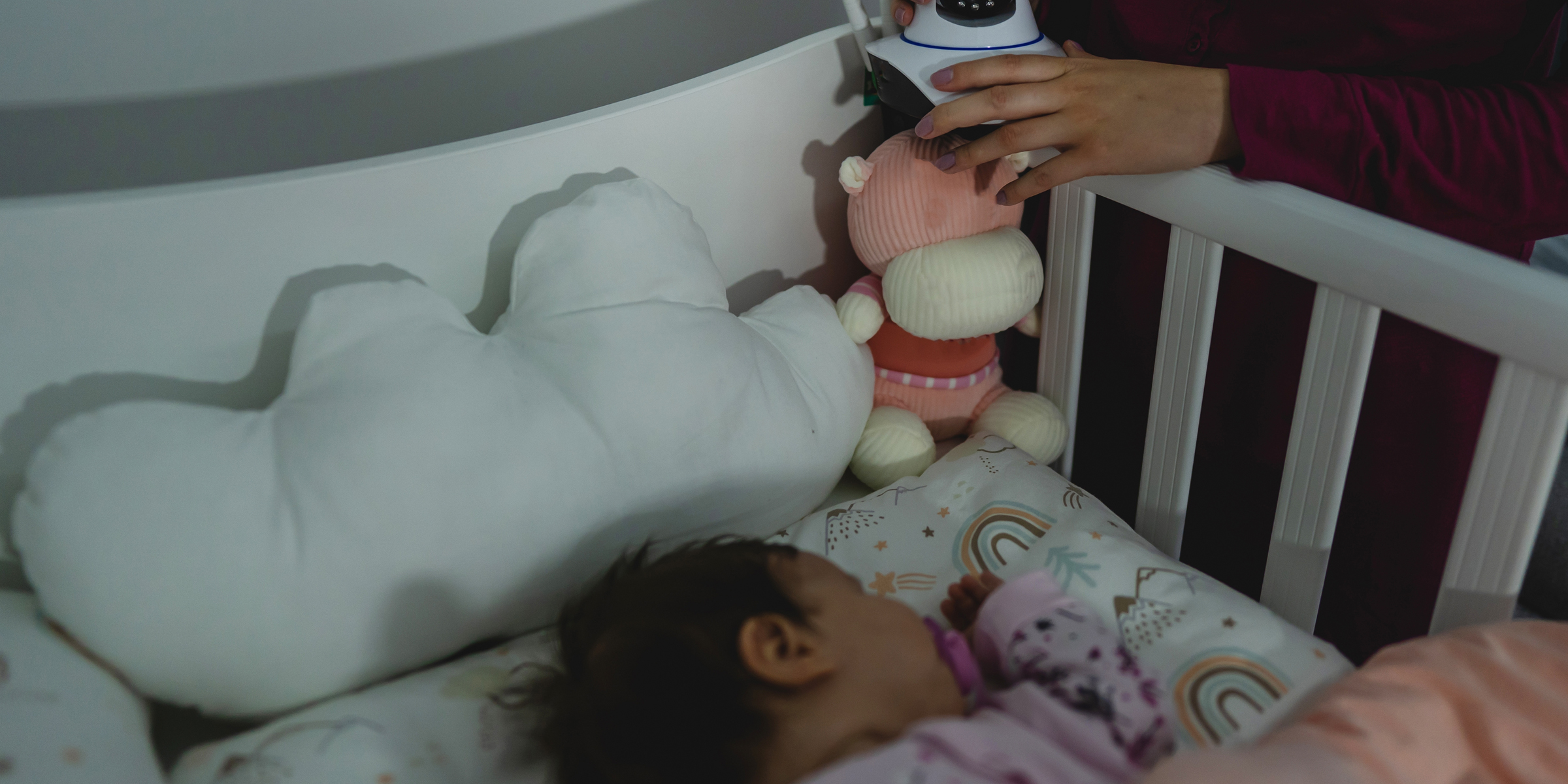 Eine Frau, die eine Kamera auf das Kinderbett eines Babys legt | Quelle: Shutterstock