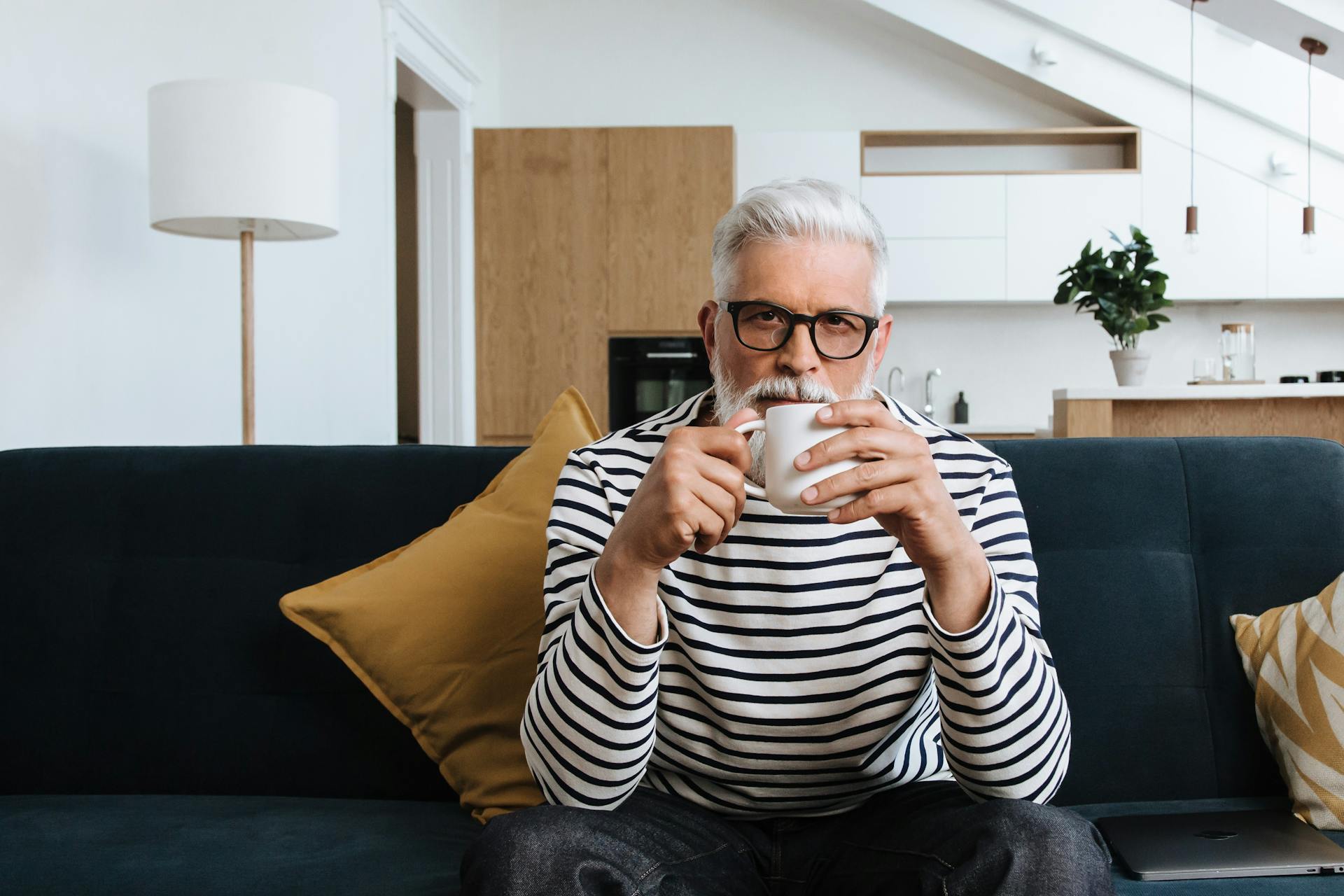 Ein älterer Mann trinkt Tee, während er auf einem Sofa sitzt | Quelle: Pexels