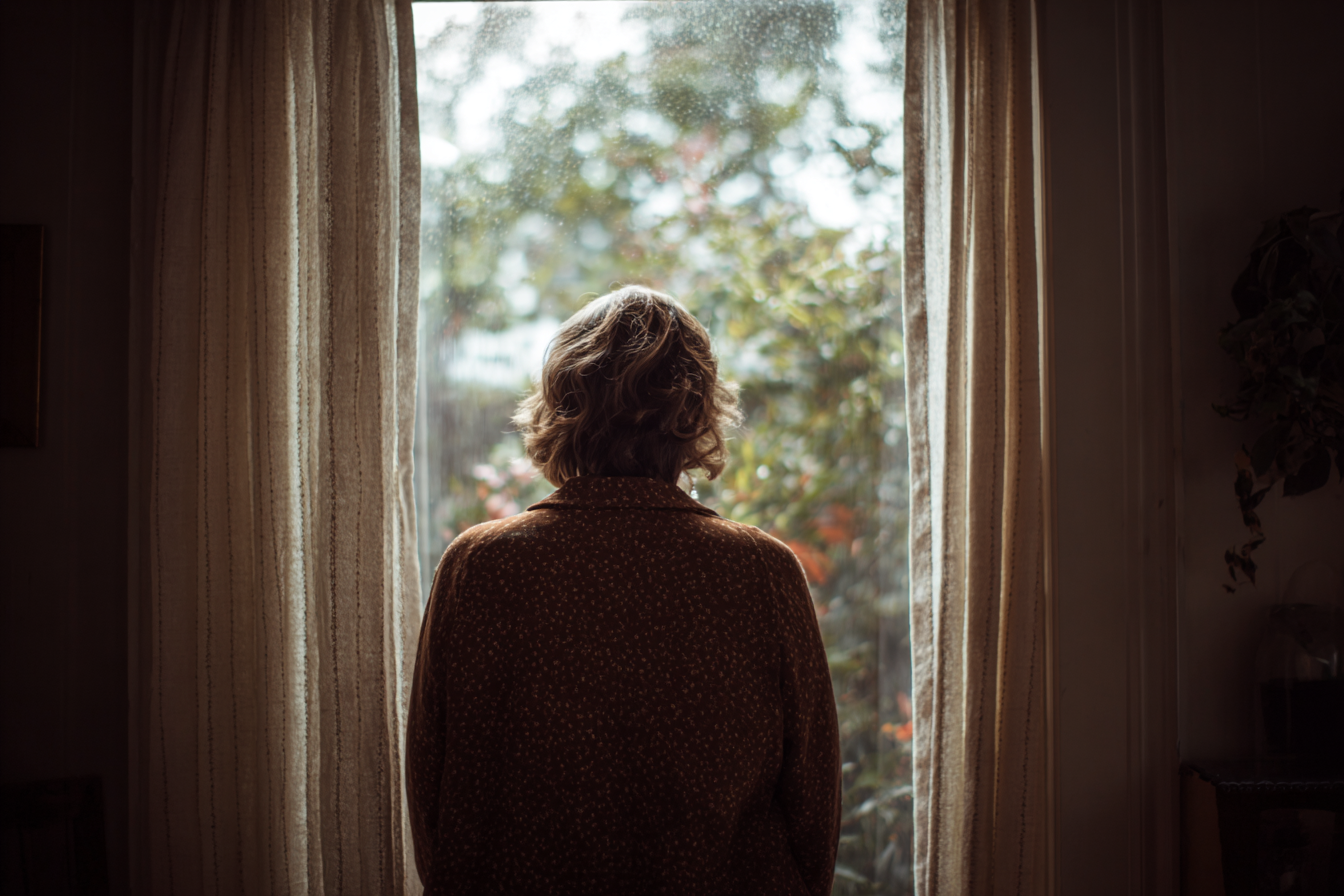 Eine Frau, die aus dem Fenster schaut | Quelle: Midjourney