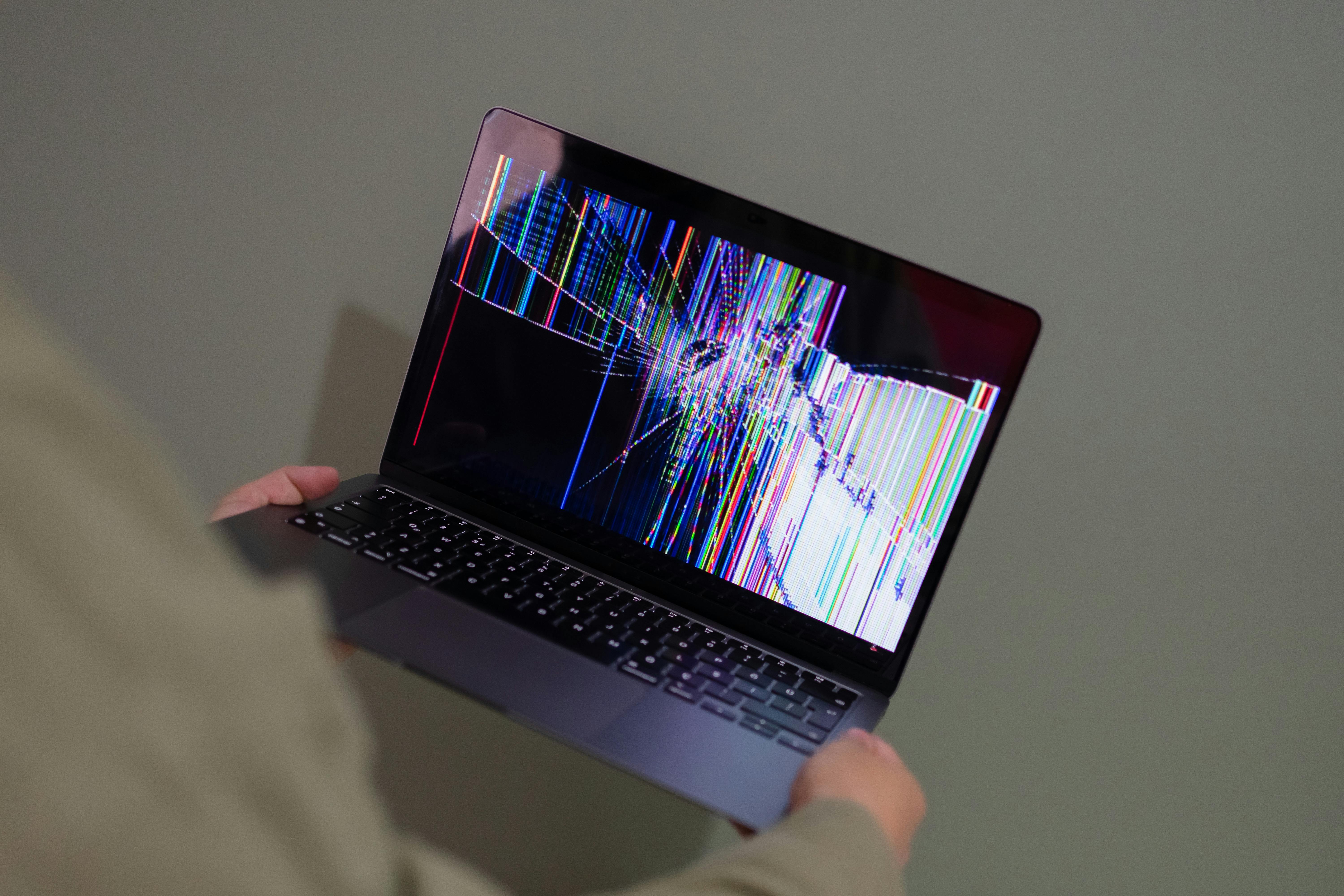Eine Person hält einen kaputten Laptop | Quelle: Pexels