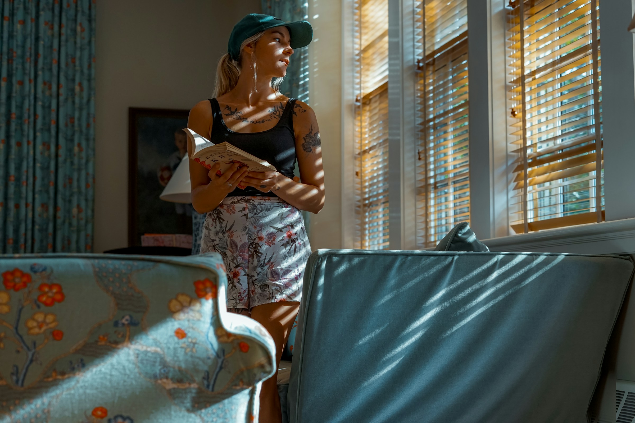 Eine Frau schaut aus dem Fenster und hält ein Buch in der Hand | Quelle: Unsplash
