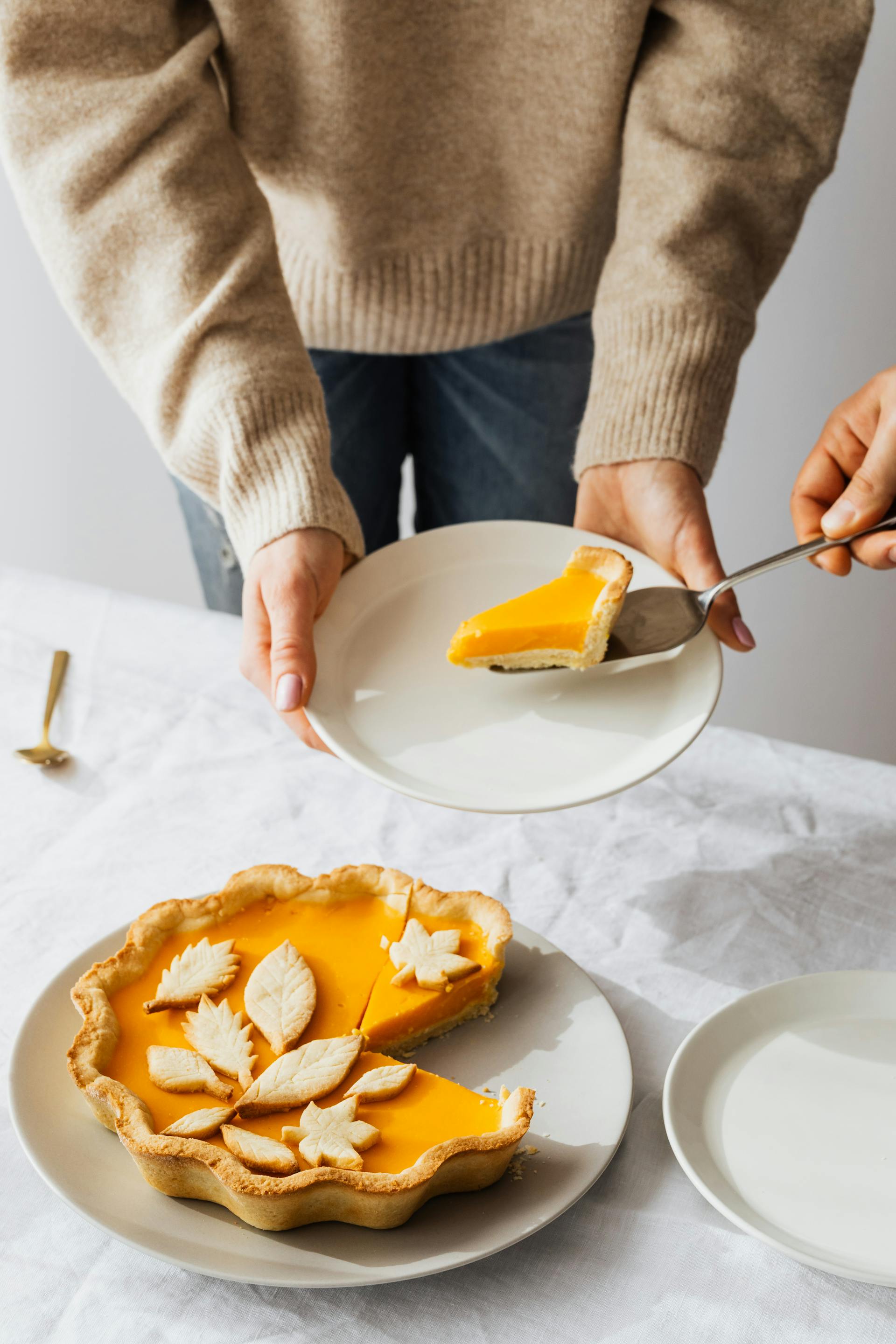 Ein Stück Zitronenkuchen auf einem Teller, der von einer Person gehalten wird | Quelle: Pexels