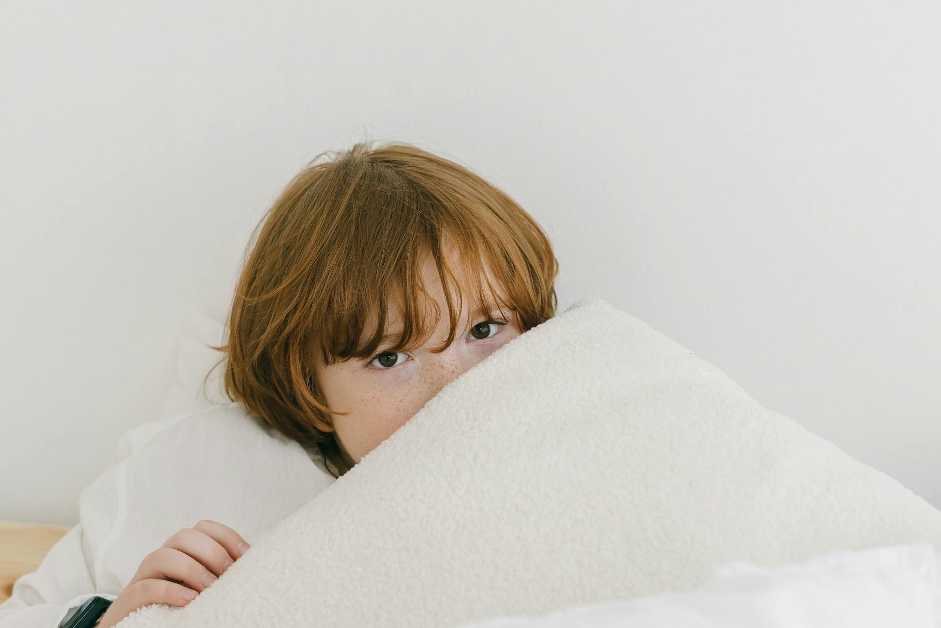 Ein Junge liegt unter seiner Decke | Quelle: Pexels