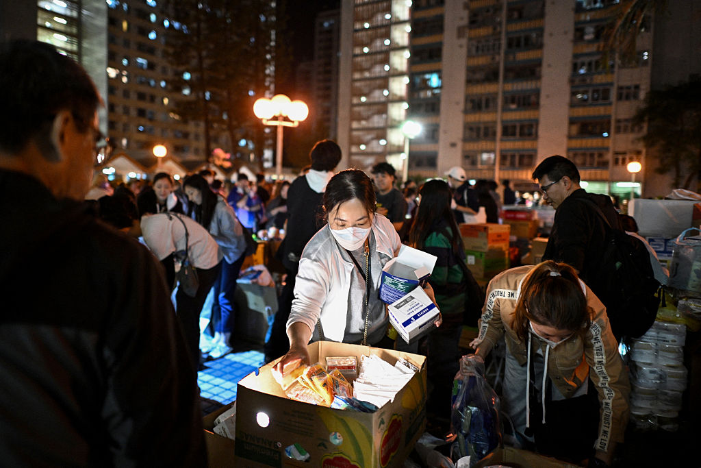 Nach dem Großbrand in der Wohnsiedlung Wang Fuk Court im Hongkonger Stadtteil Tai Po, der am 27. November 2025 auf mehrere Wohnblöcke übergriff, verteilen die Menschen die Dinge des täglichen Bedarfs. | Quelle: Getty Images