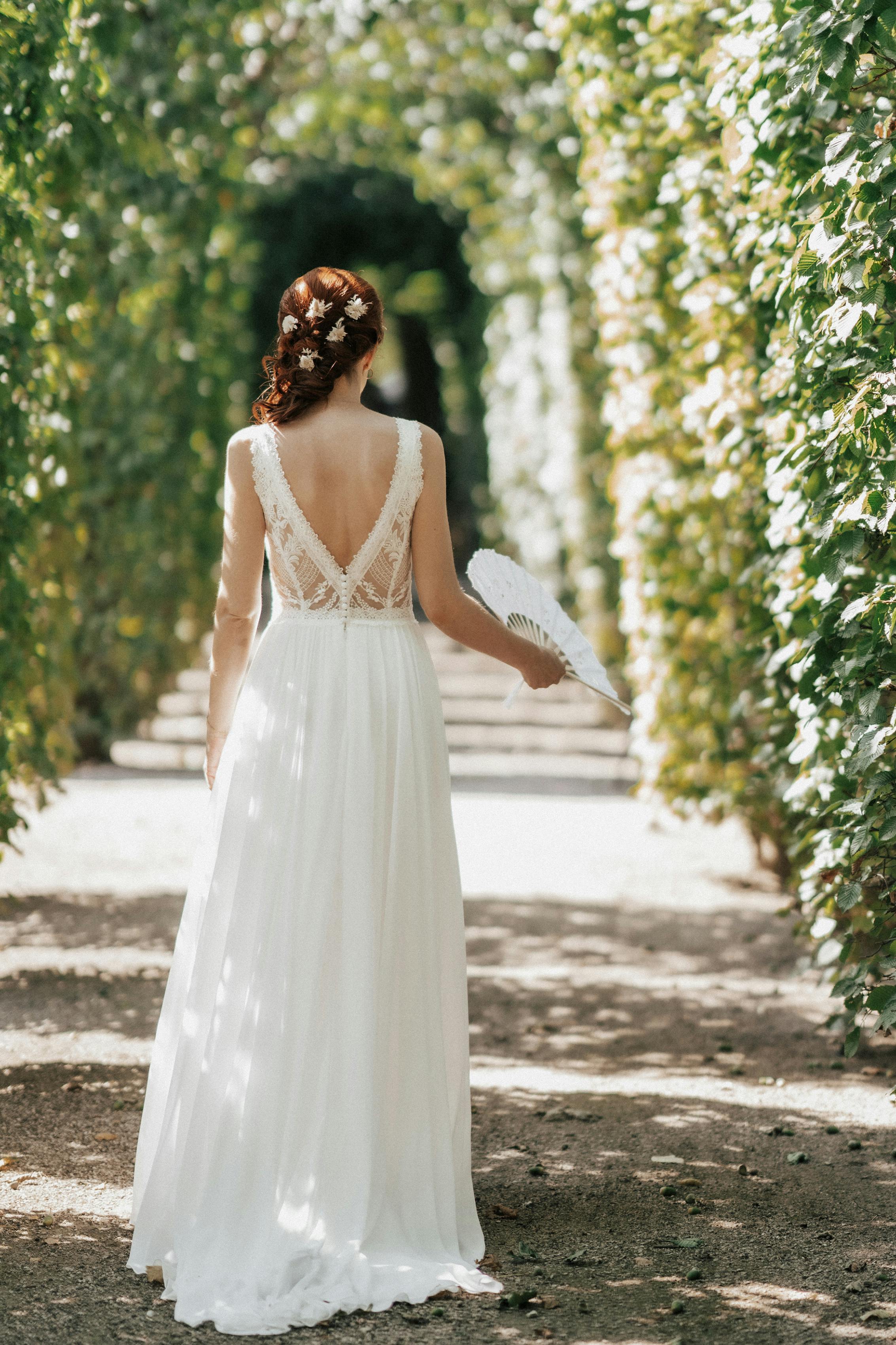 Braut im eleganten Spitzenkleid im Gartenbogen | Quelle: Pexels