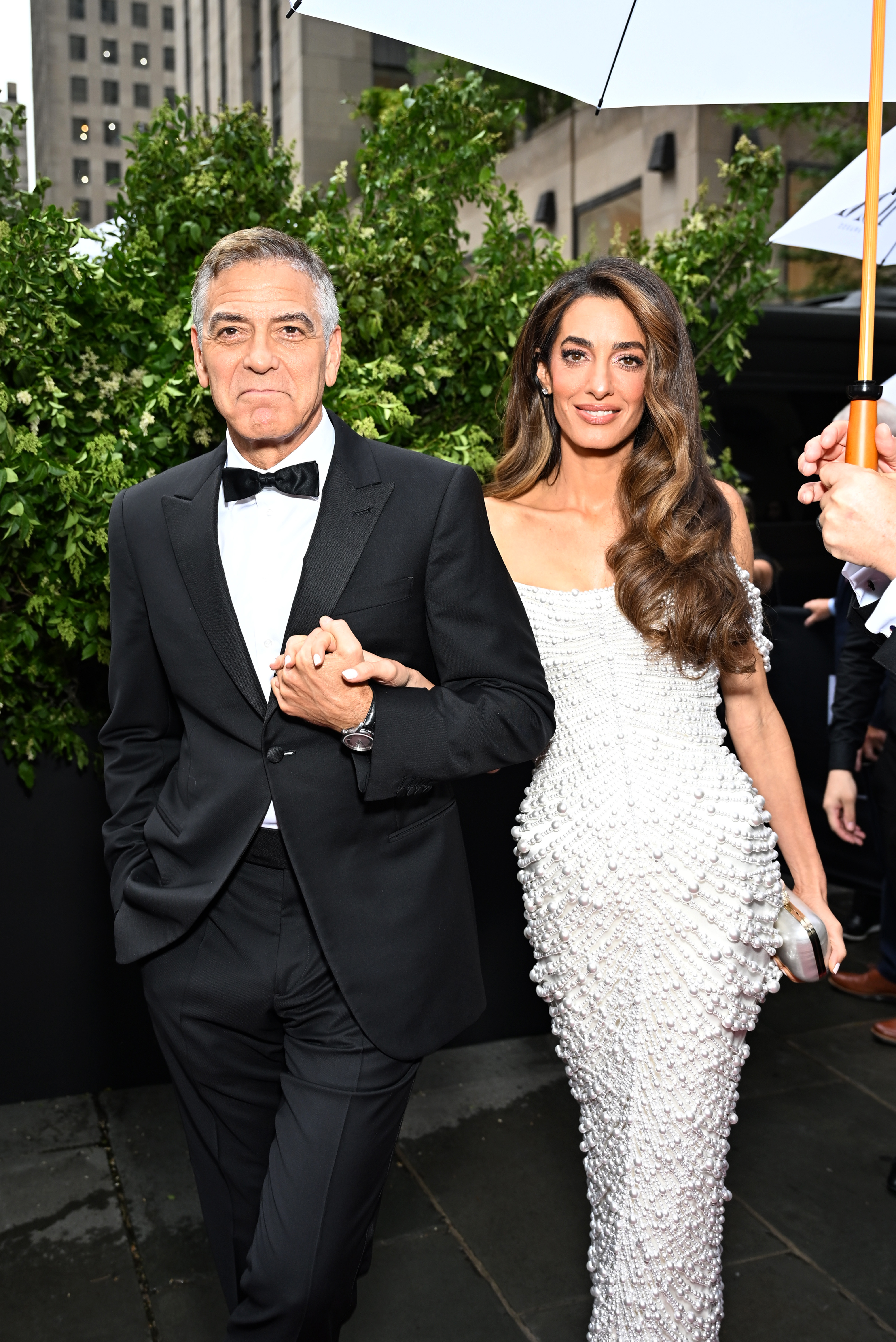 Arm in Arm nähern sich George und Amal Clooney dem Eingang der 78. Tony Awards, umrahmt von Grünpflanzen und umgeben von Mitarbeitern in einer nieseligen Nacht in Manhattan.