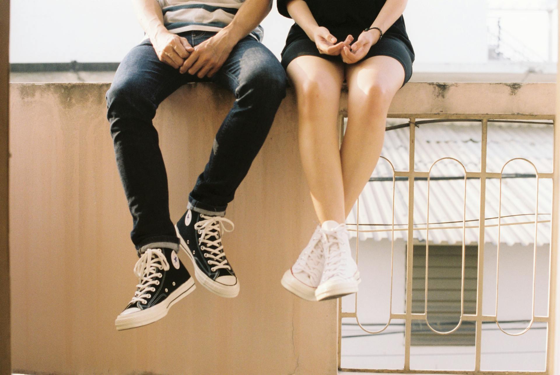 Młoda para siedząca na murku w converse | Źródło: Pexels