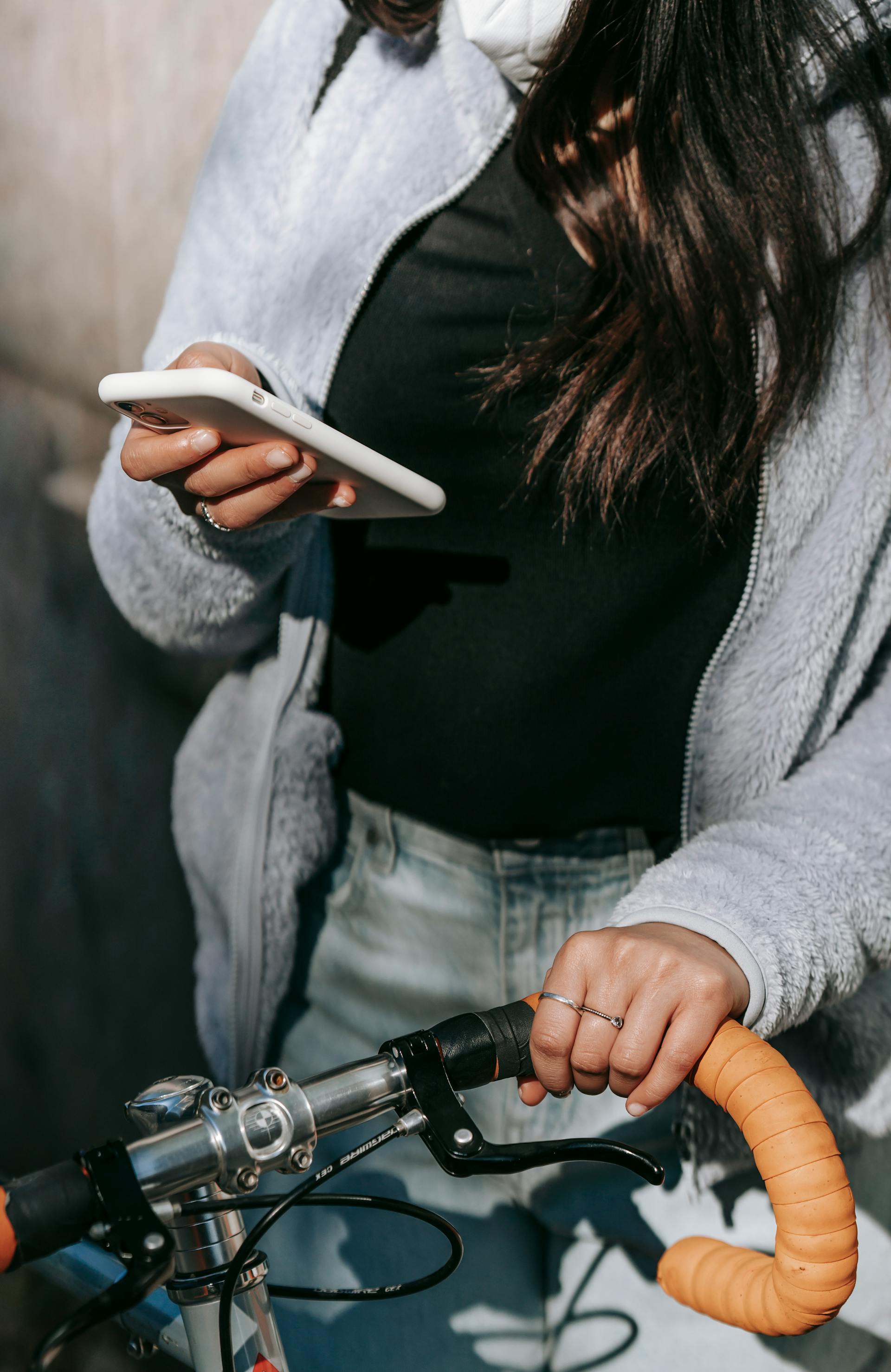 Eine junge Frau, die ihr Telefon benutzt, während sie den Griff ihres Fahrrads festhält | Quelle: Pexels
