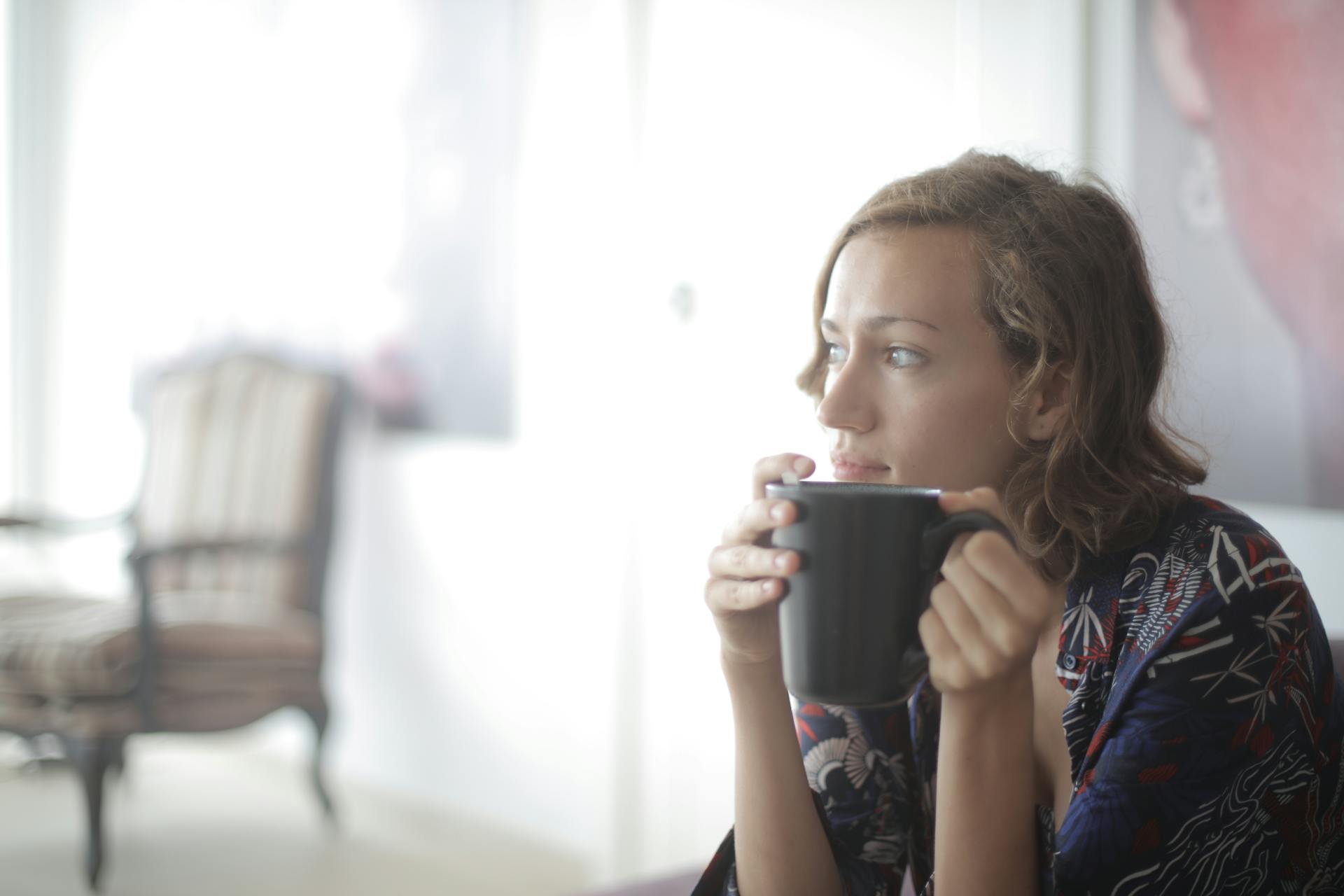 Eine Frau mit einem warmen Getränk in einem Wohnzimmer | Quelle: Pexels