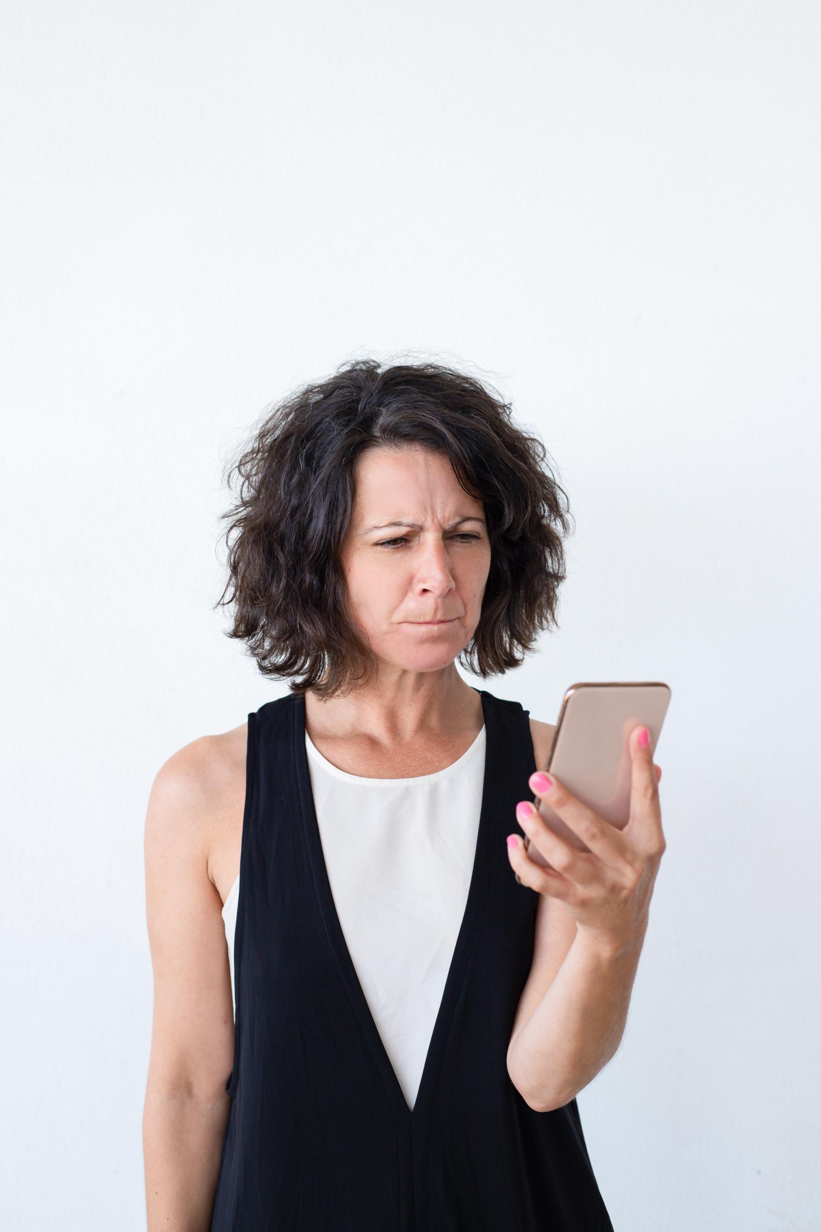 Eine verärgerte Frau schaut auf ihr Telefon | Quelle: Freepik