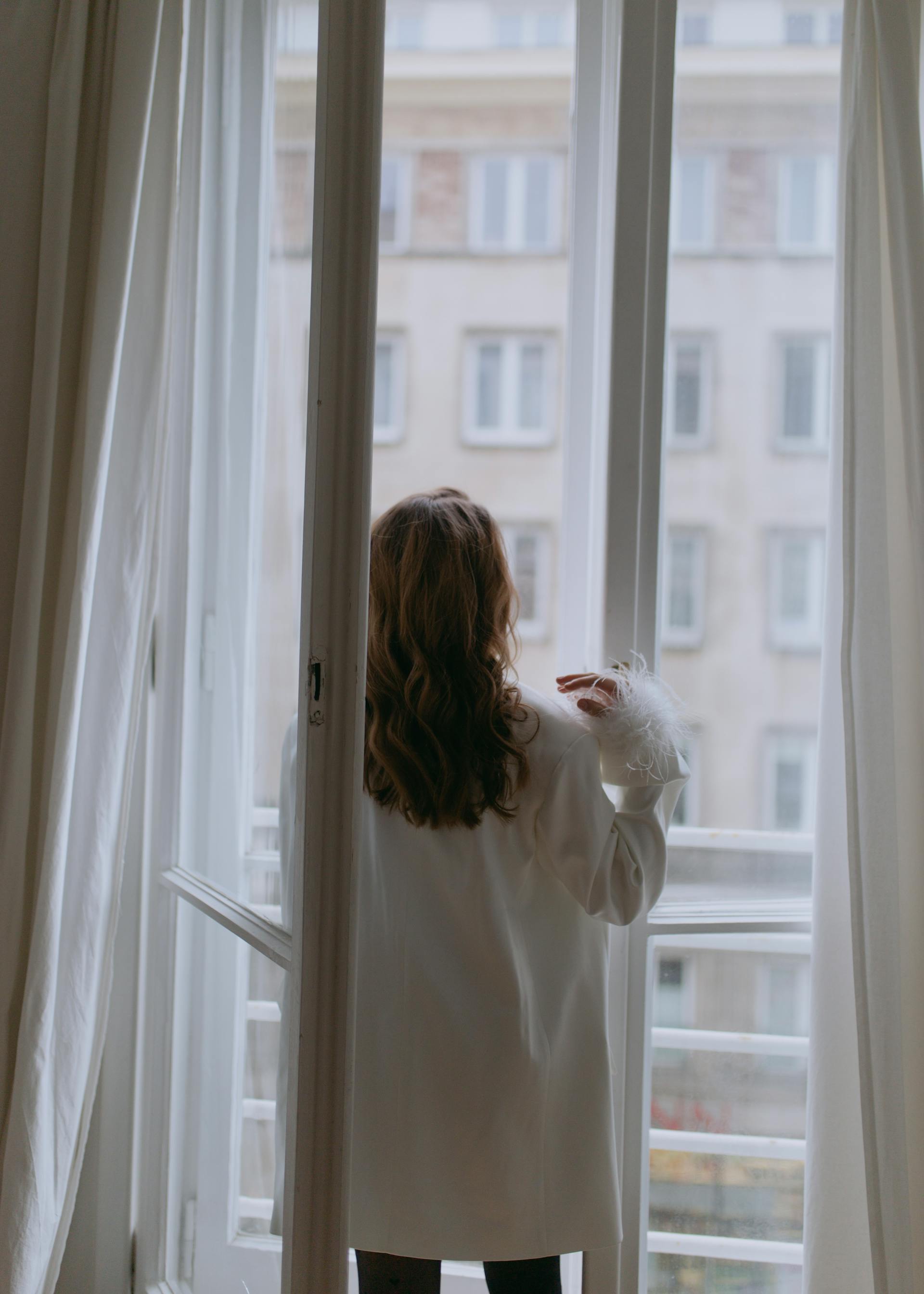 Eine Frau steht neben einem offenen Fenster | Quelle: Pexels