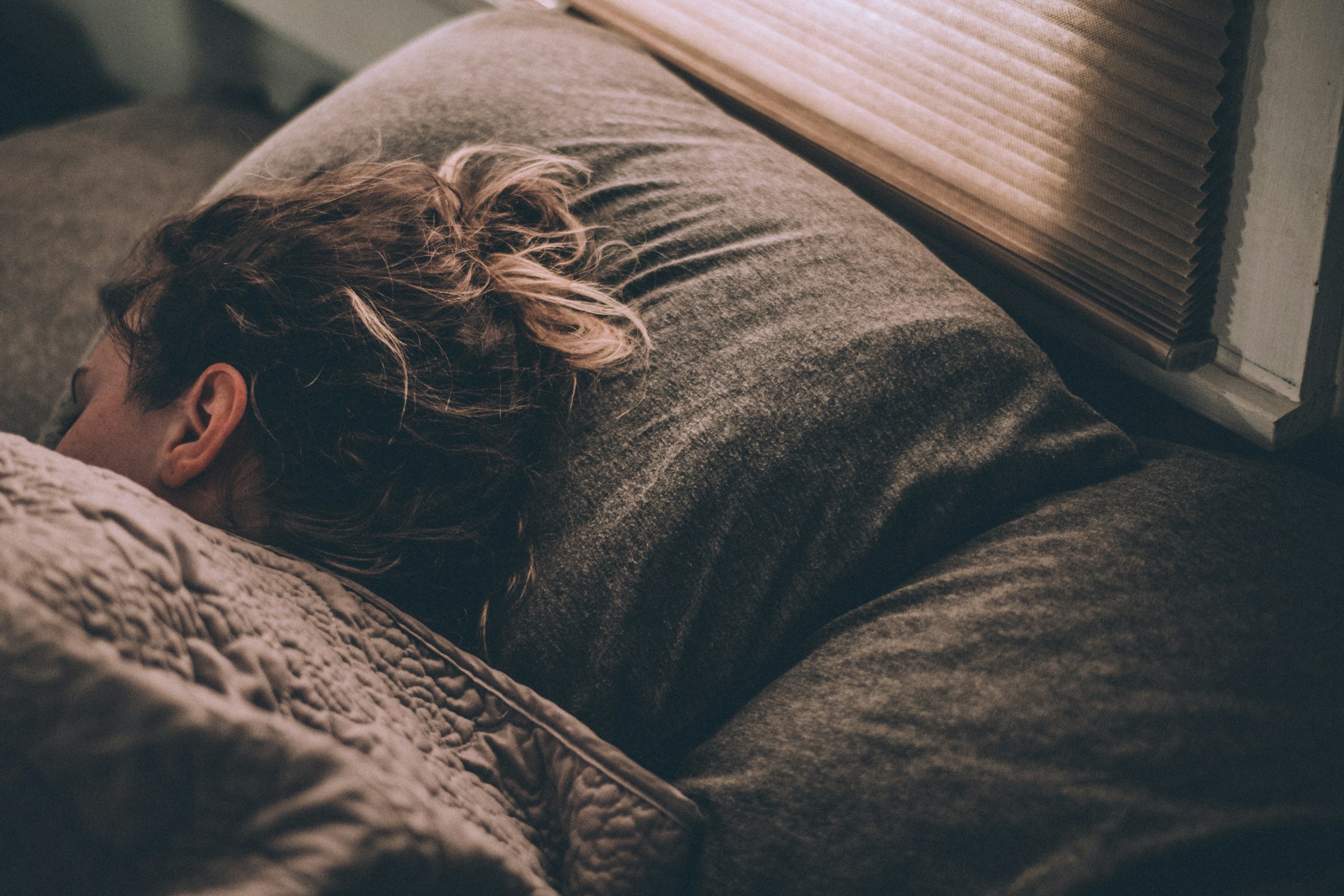 Eine Frau schläft fest in ihrem Zimmer | Quelle: Unsplash