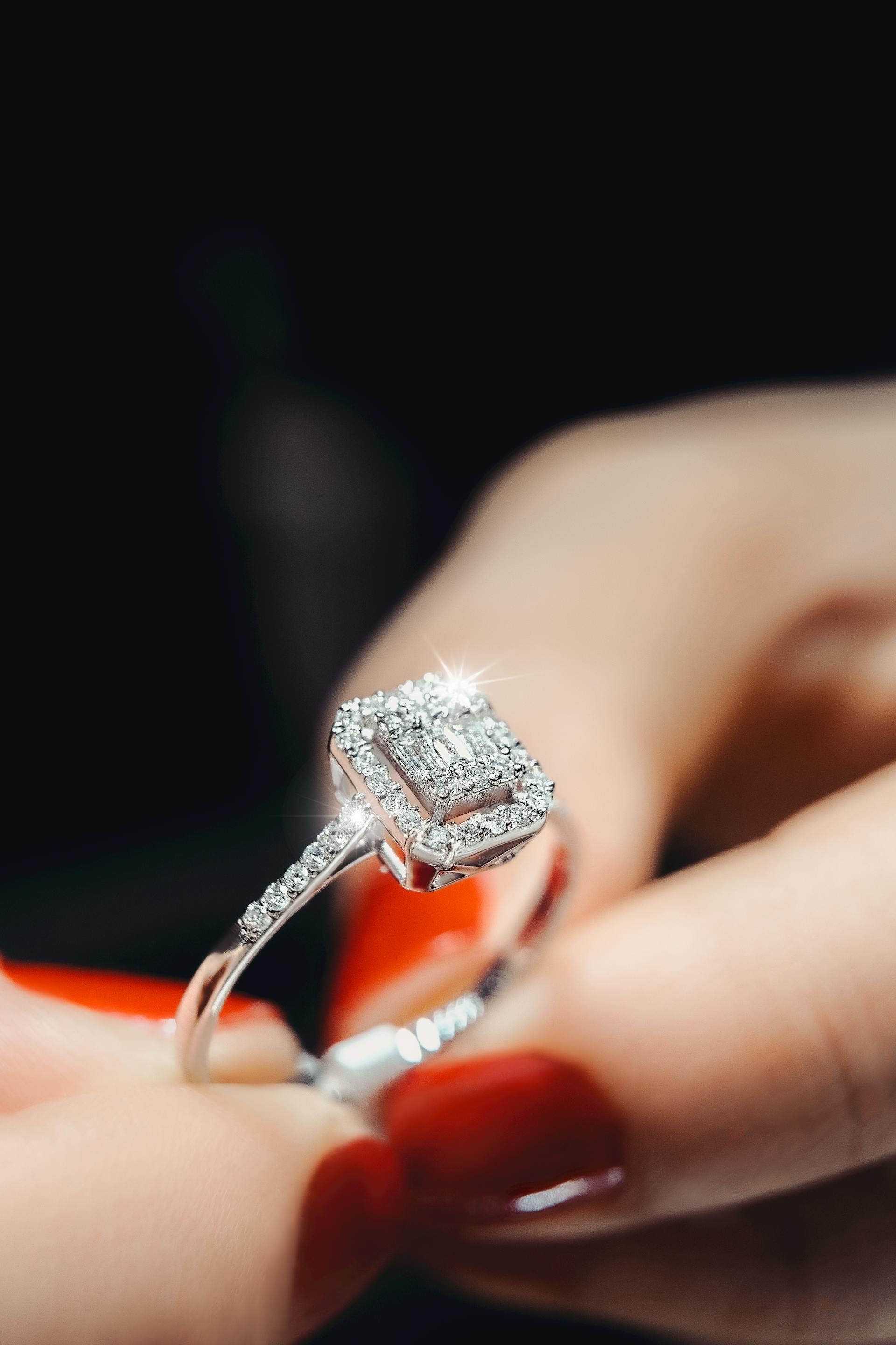 Eine Nahaufnahme der Hände einer Frau, die einen Diamantring hält | Quelle: Pexels