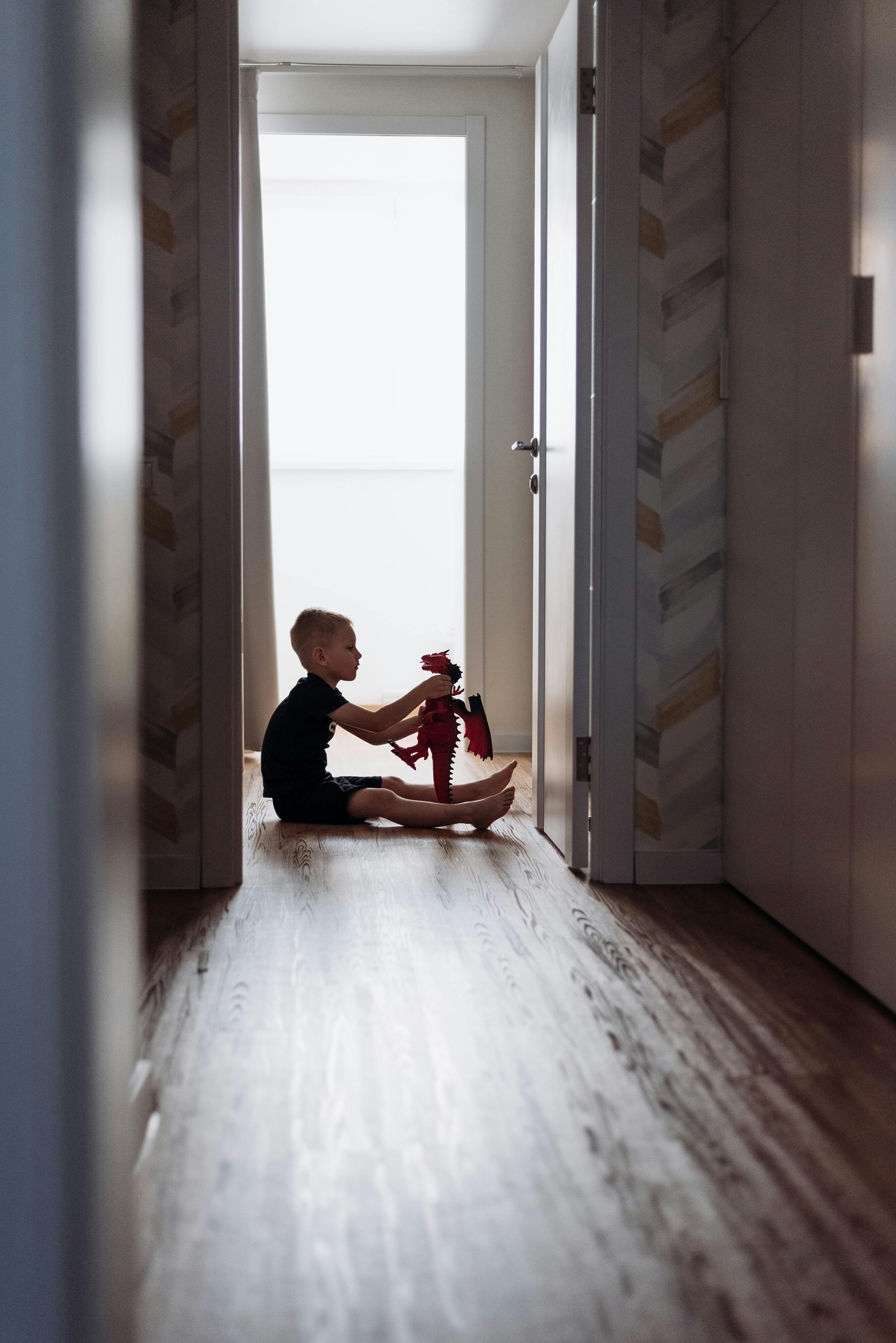 Ein Kind sitzt auf dem Boden und spielt mit einem Spielzeug | Quelle: Pexels