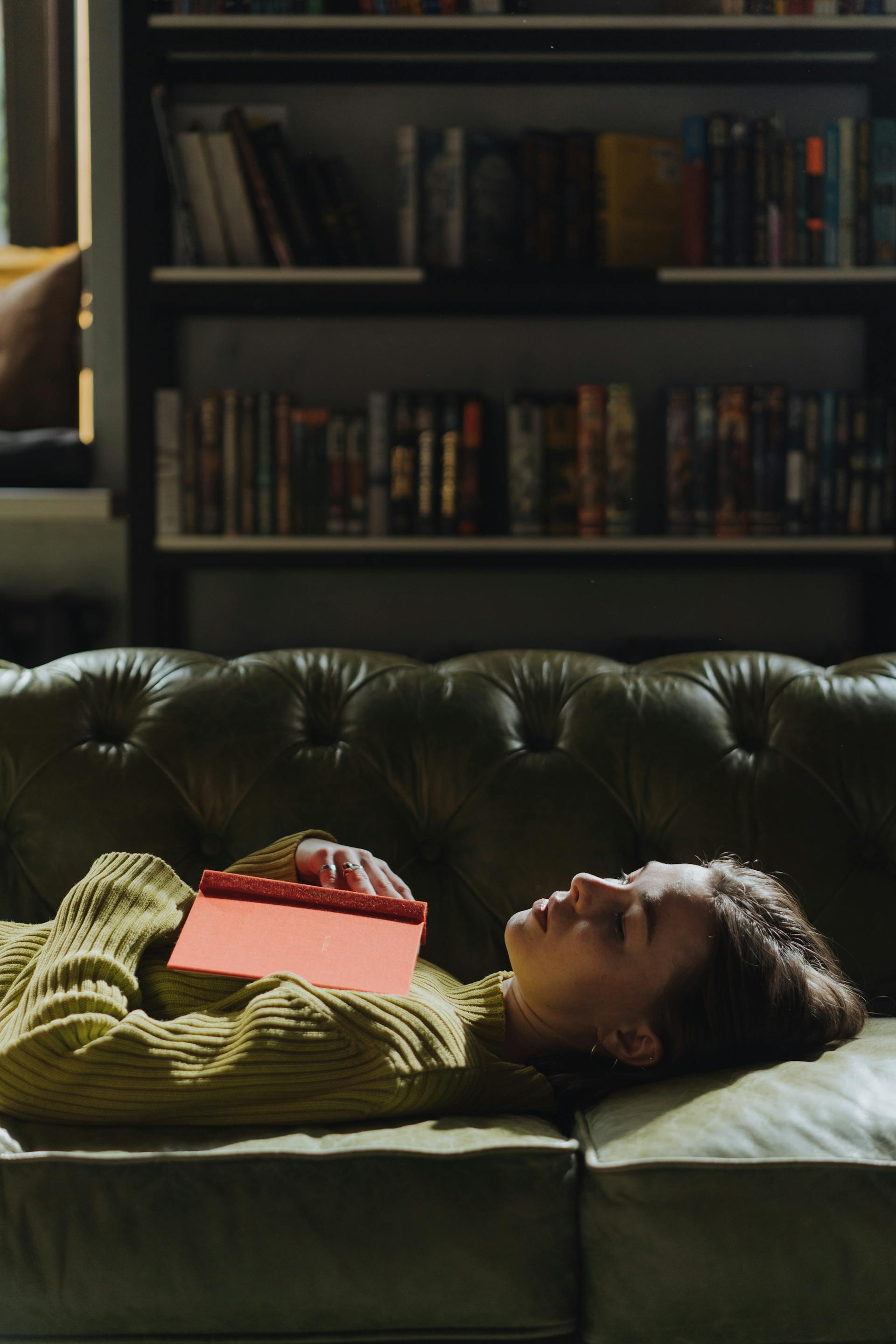 Eine Frau, die mit einem Buch auf einem Sofa liegt | Quelle: Pexels
