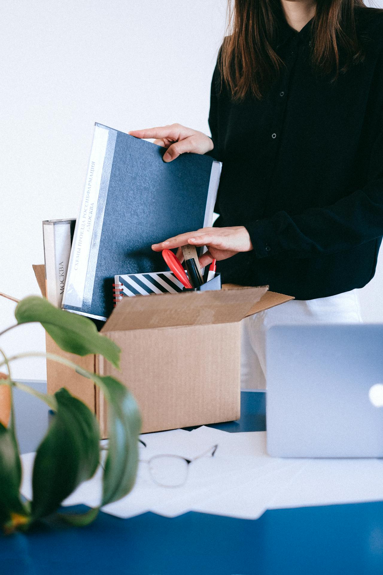Eine Frau sortiert Büromaterial in einer Kiste | Quelle: Pexels