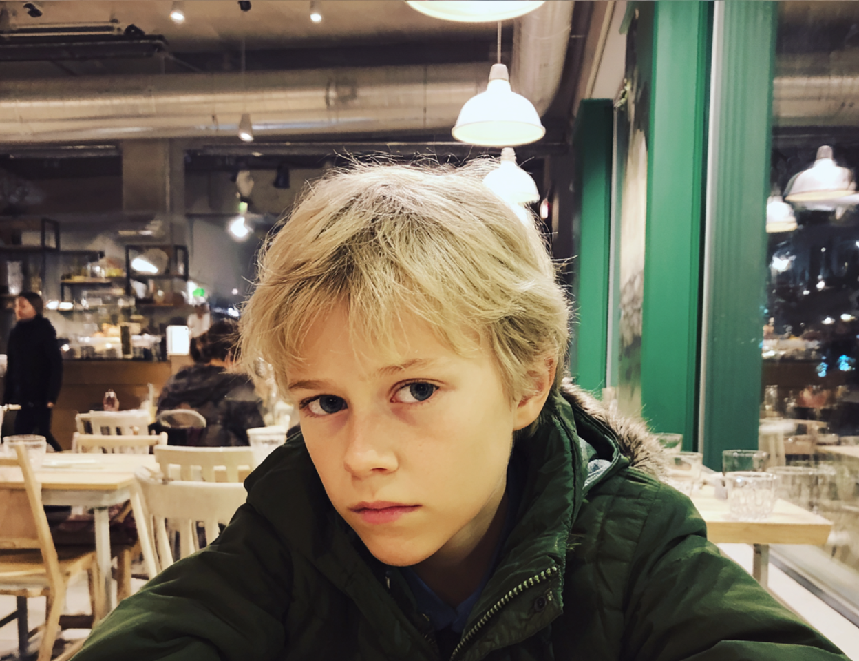 Eine Nahaufnahme eines Jungen, der an einem Tisch sitzt | Quelle: Midjourney