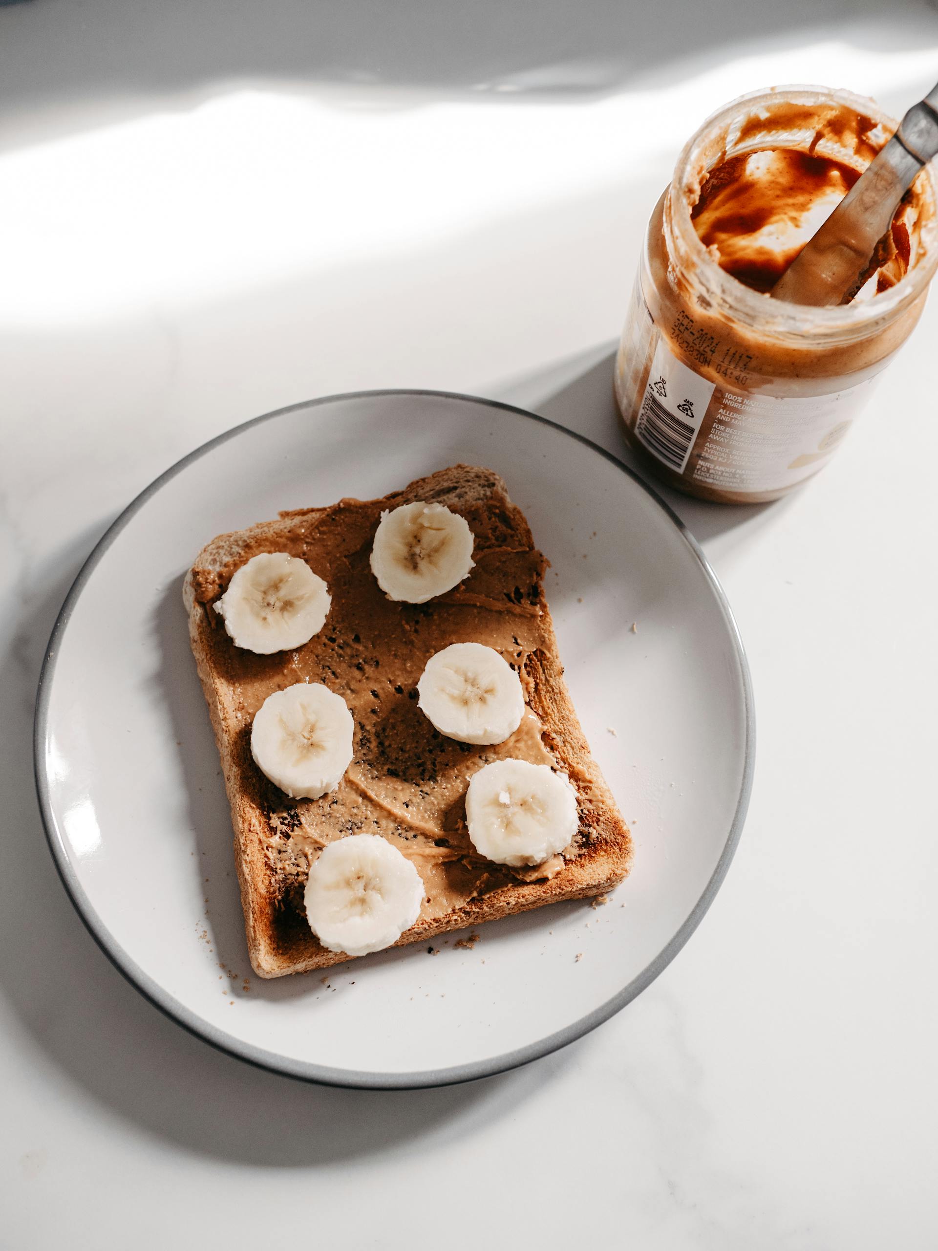 Ein offenes Glas mit Erdnussbutter und Brot | Quelle: Pexels